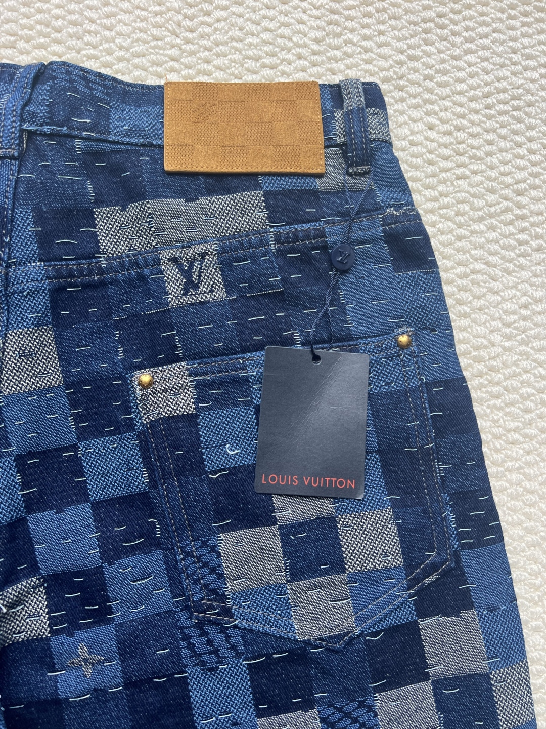 P240 LOUIS VUITTON✖️Nigo联名提花棋盘格牛仔长裤
工艺说明:这款滑板来自Pharrell Williams与Nigo合作的2025秋冬系列,采用100%纯棉面料打造,兼具舒适度与耐用性。设计上巧妙融合了品牌标志性的Damier格纹元素,通过独特的拼缝工艺向日本传统拼布技艺致敬。裤身采用经典五袋剪裁,搭配珠光纽扣前襟和铆钉装饰,细节处尽显精致。全幅标识提花工艺彰显品牌辨识度,正绒面革标签则增添了高级质感。整体版型专为滑板运动设计,既保持活动自由度又不失时尚感。可与同系列搭配,完整呈现秀场造型。珠光元素的运用与格纹图案相得益彰,展现出品牌对传统工艺与现代潮流的完美平衡。
码数:30-32-34-36
