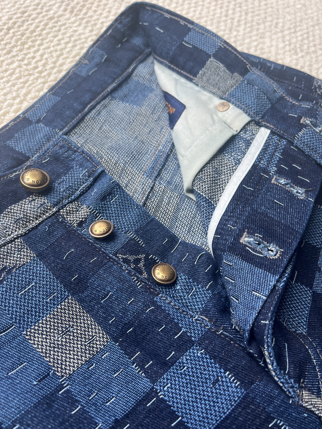 P240 LOUIS VUITTON✖️Nigo联名提花棋盘格牛仔长裤
工艺说明:这款滑板来自Pharrell Williams与Nigo合作的2025秋冬系列,采用100%纯棉面料打造,兼具舒适度与耐用性。设计上巧妙融合了品牌标志性的Damier格纹元素,通过独特的拼缝工艺向日本传统拼布技艺致敬。裤身采用经典五袋剪裁,搭配珠光纽扣前襟和铆钉装饰,细节处尽显精致。全幅标识提花工艺彰显品牌辨识度,正绒面革标签则增添了高级质感。整体版型专为滑板运动设计,既保持活动自由度又不失时尚感。可与同系列搭配,完整呈现秀场造型。珠光元素的运用与格纹图案相得益彰,展现出品牌对传统工艺与现代潮流的完美平衡。
码数:30-32-34-36