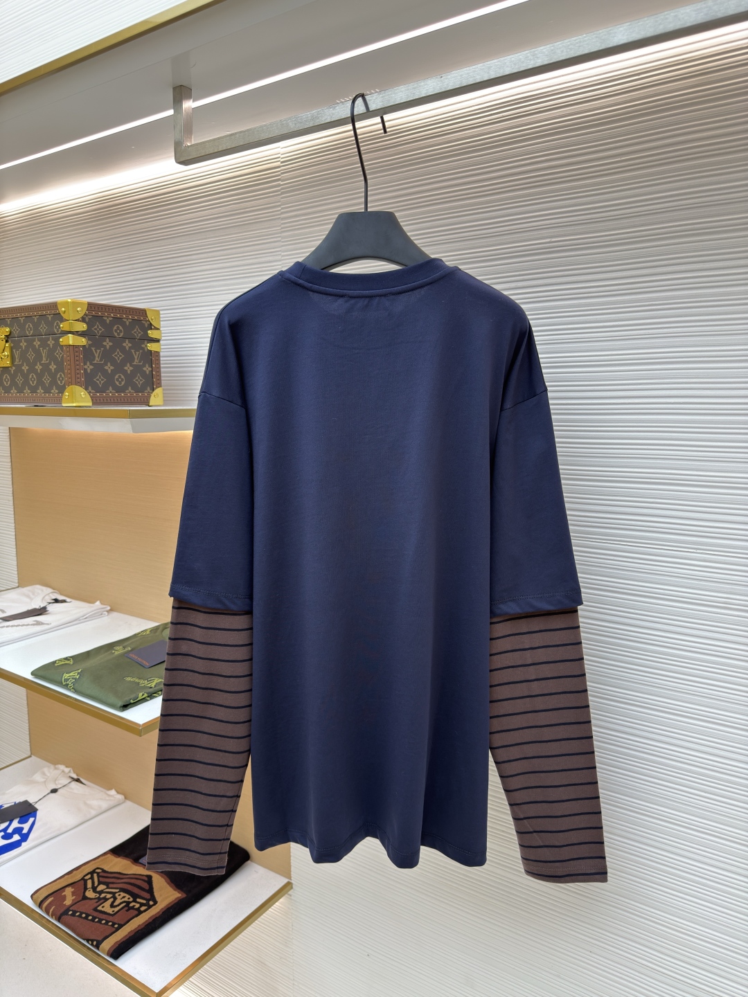 P145 MIUMIU棕条纹假两件长袖
●原版：8269购入开发
●货号：1680700-A20
●面料：棉质平纹针织面料
●工艺：针织提花制作
●版型：宽松版型
●克重：约350克
●尺码：XS-S-M-L
●描述：采用24S特纺紧密棉面料，185g；搭配32S双纱螺纹，300g。紧密纺强力比传统单纱高，紧密纱中的单纤维排列紧密，有助于提高纱线的强力。纤维的端头均捻入纱线内，因此成纱非常紧密，纱线外观光洁毛羽少。紧密纺纱线强力较高毛羽较少，不易产生磨毛的现象。采用24S提花条纹工艺特种纺织紧密棉 ，200g；搭配提花工艺复杂织造技术，通过经纬纱线的交错形成条纹图案，赋予面料立体感和层次感，视觉上更显高级。条纹通过提花工艺呈现，比普通印花或染色条纹更持久不易褪色，且纹理清晰、边界分明，经典复古与现代摩登结合的风格。通常选用混纺纱线，徽标面料柔软亲肤且不易变形。纱线支数较高织物质地细腻紧密，精细提花图案徽标增强视觉层次感。整体走线平直细腻，面料舒适柔软，颜色一致无色差 能与同款搭配营造时尚造型，驾驭各种场合，定制辅料，三标齐全，男女同款！