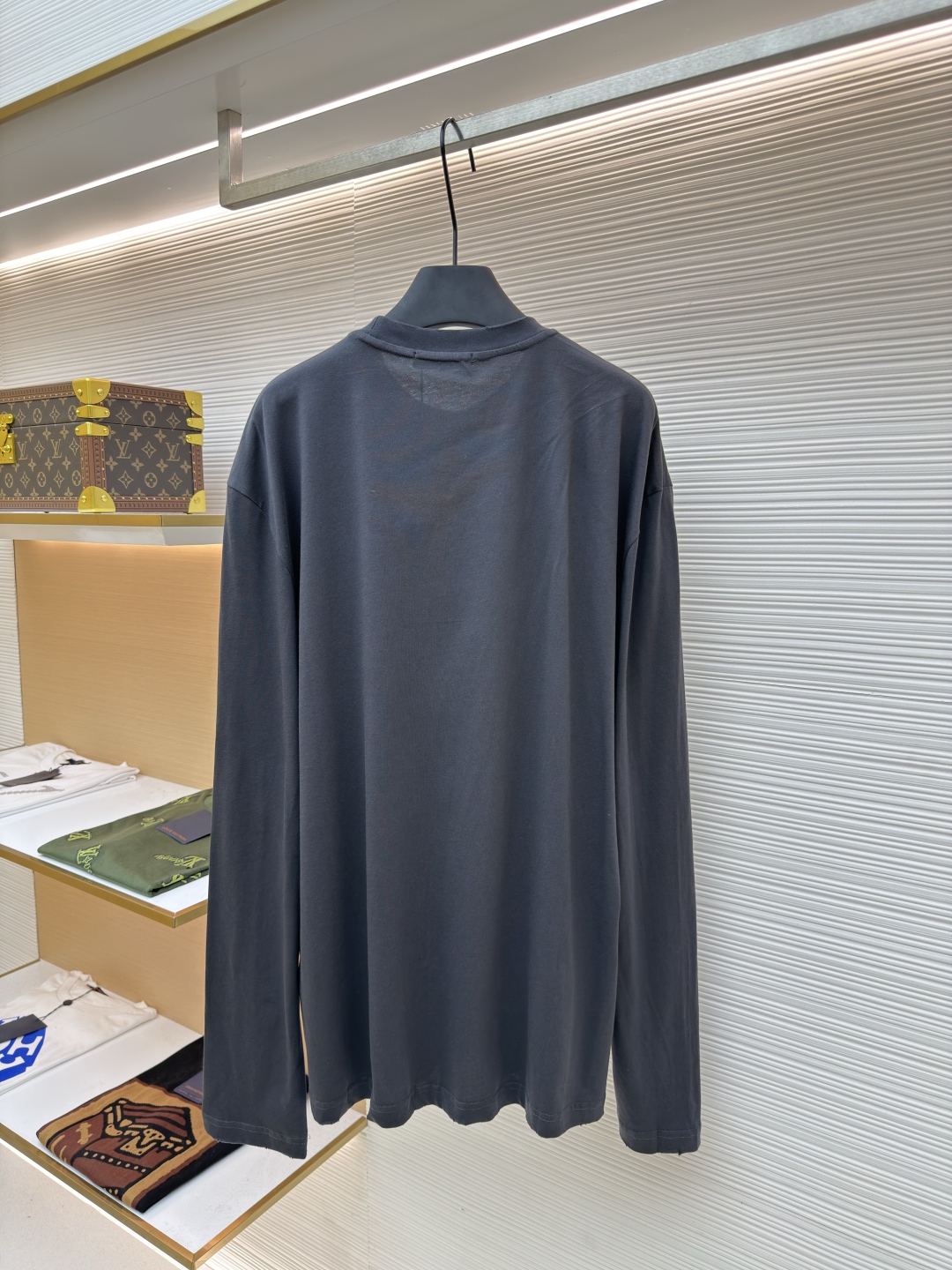 P125 Prada 铅笔灰长袖
●原版：8934购入开发
●货号:  1680720-A05
●面料：精梳平纹面料
●工艺：激光烧花制作
●版型：合身版型
●克重：约240克
●尺码：S-M-L-XL
●描述：定织50S 190G精梳平纹面料，非市场通用坯布，需从纱线配比、织机参数全程定制。通过精梳工艺去除短纤维杂质，确保纱线更长、更均匀，织物表面光洁无毛羽。  特殊定染铅笔灰色，单独调色而非使用标准色卡，需多次打样匹配Prada指定的低饱和度灰调。胸前三角激光烧花绣花定型：激光烧花：高精度激光雕刻，在面料表面碳化形成渐变蚀刻纹理，边缘需人工调试避免焦痕。  复合绣花：在烧花基础上叠加刺绣，线迹密度需与烧花图案对齐，防止面料变形。  立体定型：使用高温压烫或树脂涂层维持三角结构的浮雕感，避免洗后塌陷。整体走线平直细腻，面料舒适柔软，颜色一致无色差 能与同款搭配营造时尚造型，驾驭各种场合，定制辅料，三标齐全，男女同款！