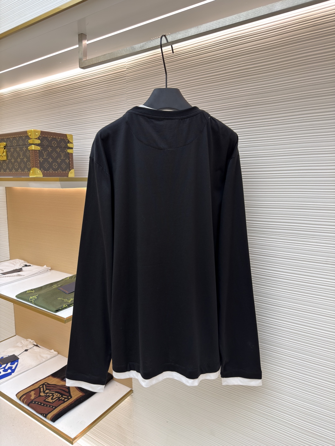 P140 Prada 三角标假两件长袖
●原版：6670购入开发
●货号：1680979-A20
●面料：精梳棉面料
●工艺：激光烧花制作
●版型：合身版型
●克重：约315克
●尺码：S-M-L
●描述：根据原版定制纱线，以达到特定的克重（200g/㎡）、厚度、韧性和手感。200克的重量确保了衣物具有良好的垂坠感和挺括度，不会轻飘也不会笨重。 “精梳” 工艺去除了棉纤维中的短绒和杂质，使得纱线更顺滑、强韧，织出的面料表面光洁、不易起球、触感细腻。“定染” 确保了颜色是专属且一致的，色彩饱和度与面料质感完美匹配，呈现出高级的单一色调。“假两件”设计是工艺智慧的体现。它并非简单地将两片布缝在一起，而是通过精密的一体化剪裁和拼接，模拟出两件衣物叠穿的层次效果。其复杂性在于无痕衔接：在领口、袖口和下摆处的拼接必须天衣无缝，模拟出内搭衣物的自然露出状态。这需要对不同面料的模拟拼接处进行特殊的滚边或压胶处理，使其边缘平整、过渡自然。整体走线平直细腻，面料舒适柔软，颜色一致无色差 能与同款搭配营造时尚造型，驾驭各种场合，定制辅料，三标齐全，男女同款！