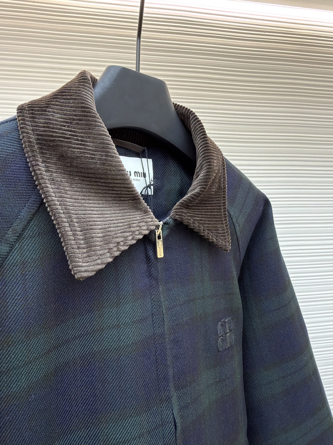 P305 MIU MIU 格纹拉链棉服外套
●原版:23999购入开发
●货号:1681460-B70
●面料:菱形衍棉面料
●工艺:刺绣制作
●版型:合身版型
●克重:约1025克
●尺码:38-40-42
●描述:该夹克采用格纹面料拼接工艺,选用深绿与藏青格纹呢料,纹理清晰且质感厚重,为服装奠定复古高级的基调。细节工艺上,领口、袖口及下摆运用灯芯绒与罗纹针织拼接工艺,灯芯绒领口挺括有型,罗纹部件则增强了穿着的贴合度与舒适度,不同材质的碰撞展现出工艺的层次感。胸前品牌徽标采用立体压印工艺,低调且富有质感,与格纹面料相得益彰。衣身的拉链、口袋纽扣等五金配件均经过精细打磨,保障实用性的同时提升整体精致度。从面料选择到拼接设计,每一处工艺都体现出对复古风格与品质的双重追求,打造出兼具时尚感与实穿性的单品。整体走线平直细腻,面料舒适柔软,颜色一致无色差 能与同款搭配营造时尚造型,驾驭各种场合,定制辅料,三标齐全,男女同款!