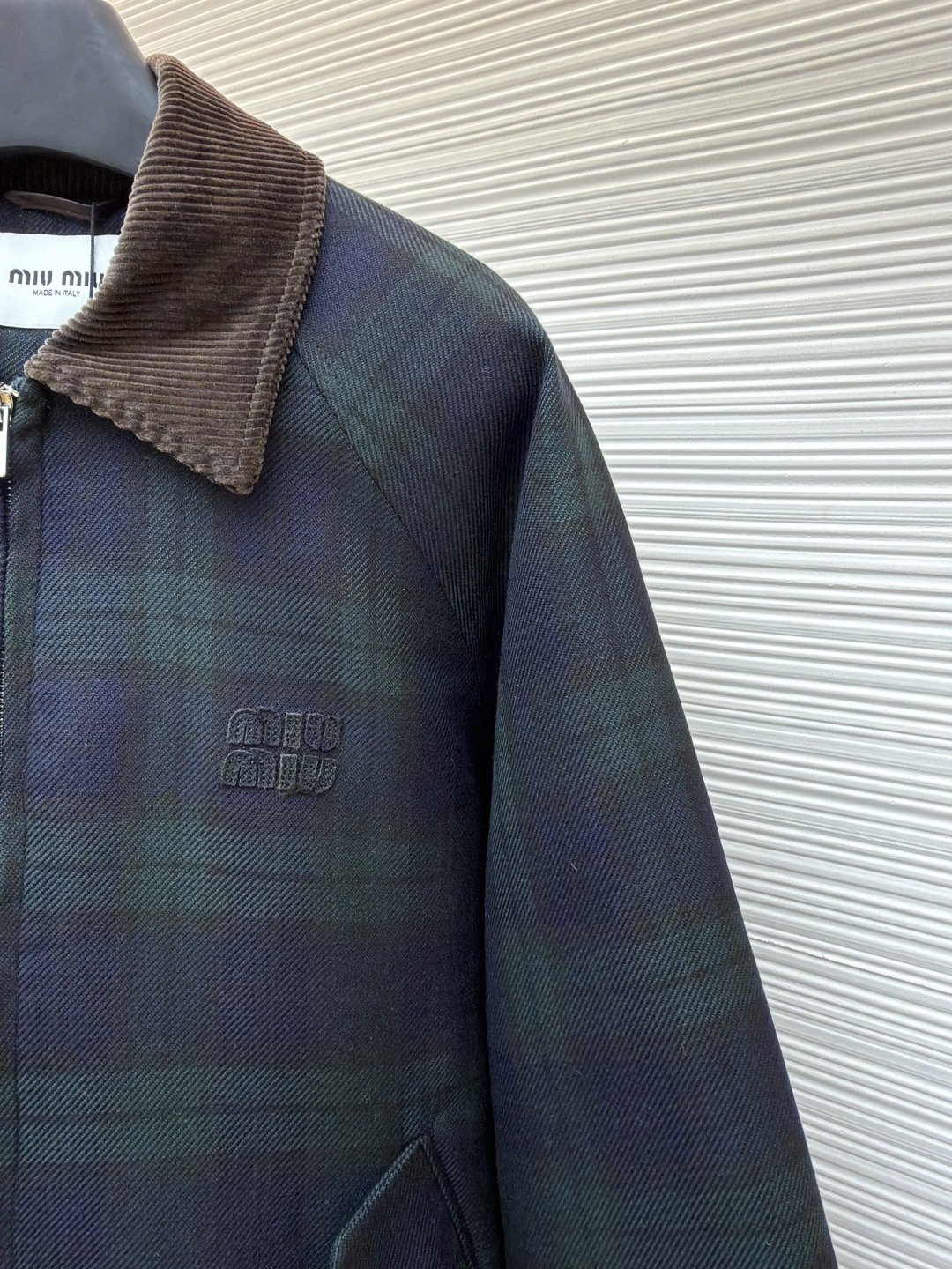 P305 MIU MIU 格纹拉链棉服外套
●原版:23999购入开发
●货号:1681460-B70
●面料:菱形衍棉面料
●工艺:刺绣制作
●版型:合身版型
●克重:约1025克
●尺码:38-40-42
●描述:该夹克采用格纹面料拼接工艺,选用深绿与藏青格纹呢料,纹理清晰且质感厚重,为服装奠定复古高级的基调。细节工艺上,领口、袖口及下摆运用灯芯绒与罗纹针织拼接工艺,灯芯绒领口挺括有型,罗纹部件则增强了穿着的贴合度与舒适度,不同材质的碰撞展现出工艺的层次感。胸前品牌徽标采用立体压印工艺,低调且富有质感,与格纹面料相得益彰。衣身的拉链、口袋纽扣等五金配件均经过精细打磨,保障实用性的同时提升整体精致度。从面料选择到拼接设计,每一处工艺都体现出对复古风格与品质的双重追求,打造出兼具时尚感与实穿性的单品。整体走线平直细腻,面料舒适柔软,颜色一致无色差 能与同款搭配营造时尚造型,驾驭各种场合,定制辅料,三标齐全,男女同款!