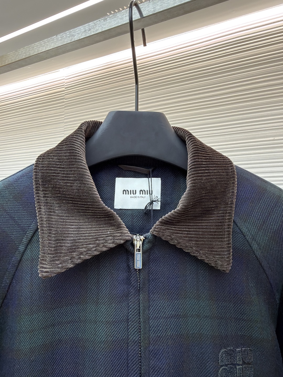 P305 MIU MIU 格纹拉链棉服外套
●原版:23999购入开发
●货号:1681460-B70
●面料:菱形衍棉面料
●工艺:刺绣制作
●版型:合身版型
●克重:约1025克
●尺码:38-40-42
●描述:该夹克采用格纹面料拼接工艺,选用深绿与藏青格纹呢料,纹理清晰且质感厚重,为服装奠定复古高级的基调。细节工艺上,领口、袖口及下摆运用灯芯绒与罗纹针织拼接工艺,灯芯绒领口挺括有型,罗纹部件则增强了穿着的贴合度与舒适度,不同材质的碰撞展现出工艺的层次感。胸前品牌徽标采用立体压印工艺,低调且富有质感,与格纹面料相得益彰。衣身的拉链、口袋纽扣等五金配件均经过精细打磨,保障实用性的同时提升整体精致度。从面料选择到拼接设计,每一处工艺都体现出对复古风格与品质的双重追求,打造出兼具时尚感与实穿性的单品。整体走线平直细腻,面料舒适柔软,颜色一致无色差 能与同款搭配营造时尚造型,驾驭各种场合,定制辅料,三标齐全,男女同款!