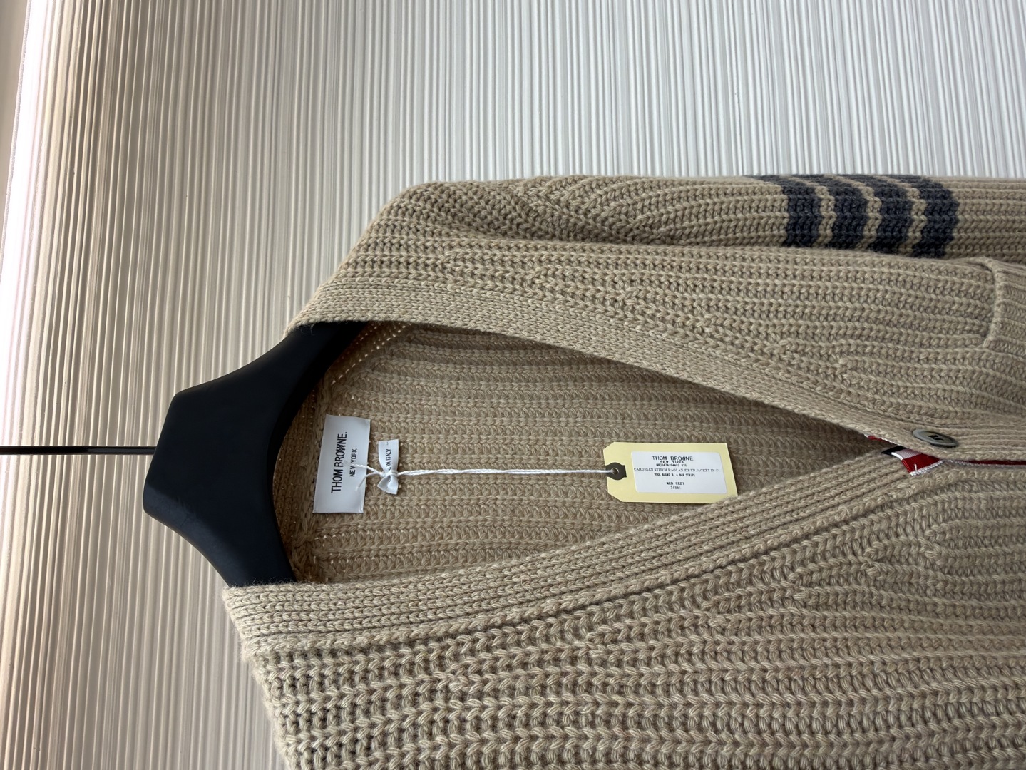 P365 THOM BROWNE四杠加厚元宝针开衫
●货号:1681466-C30
●面料:混纺面料
●工艺:针织制作
●颜色:驼色
●版型:宽松版型
●克重:约570克
●尺码:1-2-3-4
●描述:该开衫采用粗针针织工艺,选用质感细腻的纱线编织,衣身纹理粗犷且富有层次,营造出复古休闲的风格。细节工艺上,左臂的四条纹撞色针织工艺是品牌标志性设计,条纹与主色的搭配精准且富有辨识度;门襟与下摆的金属纽扣工艺,纽扣质感厚重,做工精细,既具实用性又提升了整体精致度;双贴袋的立体针织工艺,袋型挺括,与衣身针织纹理浑然一体。从粗针编织的整体质感,到条纹、纽扣、口袋的细节处理,每一处工艺都体现出品牌对经典风格与精湛工艺的坚持,打造出兼具辨识度与品质感的针织单品。整体走线平直细腻,面料舒适柔软,颜色一致无色差 能与同款搭配营造时尚造型,驾驭各种场合,定制辅料,三标齐全,男女同款!