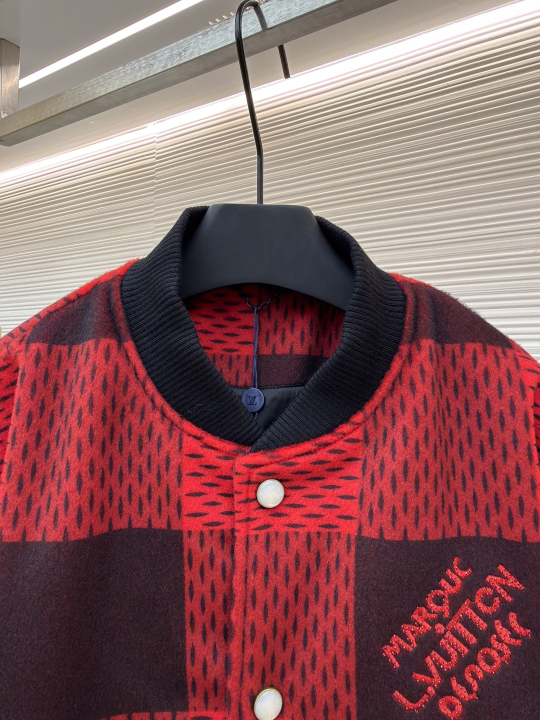 P330 LOUIS VUITTON 格纹Logo字母串珠刺绣夹克
●原版：45646购入开发
●货号：1681758-B95
●面料：羊毛混纺面料
●工艺：串珠刺绣制作
●颜色：红黑格子
●版型：合身版型
●克重：约1250克
●尺码：46-48-50-52
●描述：主体采用撞色格纹针织面料，通过提花编织工艺打造纹理层次，触感柔软且版型挺括；袖子拼接哑光皮革材质，经防刮耐磨处理，兼具质感与耐用性。衣身装饰品牌字母标识，采用立体绣线工艺，色彩鲜明且纹理清晰，强化辨识度。版型为合身棒球领设计，搭配珍珠纽扣开合，穿脱便捷；罗纹领口、袖口及下摆增强贴合度，兼顾防风性与休闲感。全衣拼接处采用精密锁边工艺，无外露线头，手工测量尺寸（误差1-3CM属正常），工艺平衡了针织的柔和与皮革的硬朗，呈现品牌潮流高级风格。整体走线平直细腻，面料舒适柔软，颜色一致无色差 能与同款搭配营造时尚造型，驾驭各种场合，定制辅料，三标齐全，男女同款！
