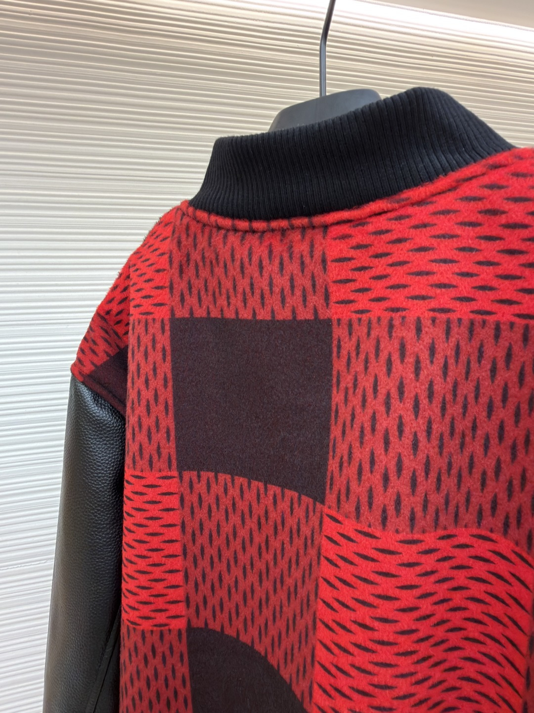 P330 LOUIS VUITTON 格纹Logo字母串珠刺绣夹克
●原版：45646购入开发
●货号：1681758-B95
●面料：羊毛混纺面料
●工艺：串珠刺绣制作
●颜色：红黑格子
●版型：合身版型
●克重：约1250克
●尺码：46-48-50-52
●描述：主体采用撞色格纹针织面料，通过提花编织工艺打造纹理层次，触感柔软且版型挺括；袖子拼接哑光皮革材质，经防刮耐磨处理，兼具质感与耐用性。衣身装饰品牌字母标识，采用立体绣线工艺，色彩鲜明且纹理清晰，强化辨识度。版型为合身棒球领设计，搭配珍珠纽扣开合，穿脱便捷；罗纹领口、袖口及下摆增强贴合度，兼顾防风性与休闲感。全衣拼接处采用精密锁边工艺，无外露线头，手工测量尺寸（误差1-3CM属正常），工艺平衡了针织的柔和与皮革的硬朗，呈现品牌潮流高级风格。整体走线平直细腻，面料舒适柔软，颜色一致无色差 能与同款搭配营造时尚造型，驾驭各种场合，定制辅料，三标齐全，男女同款！