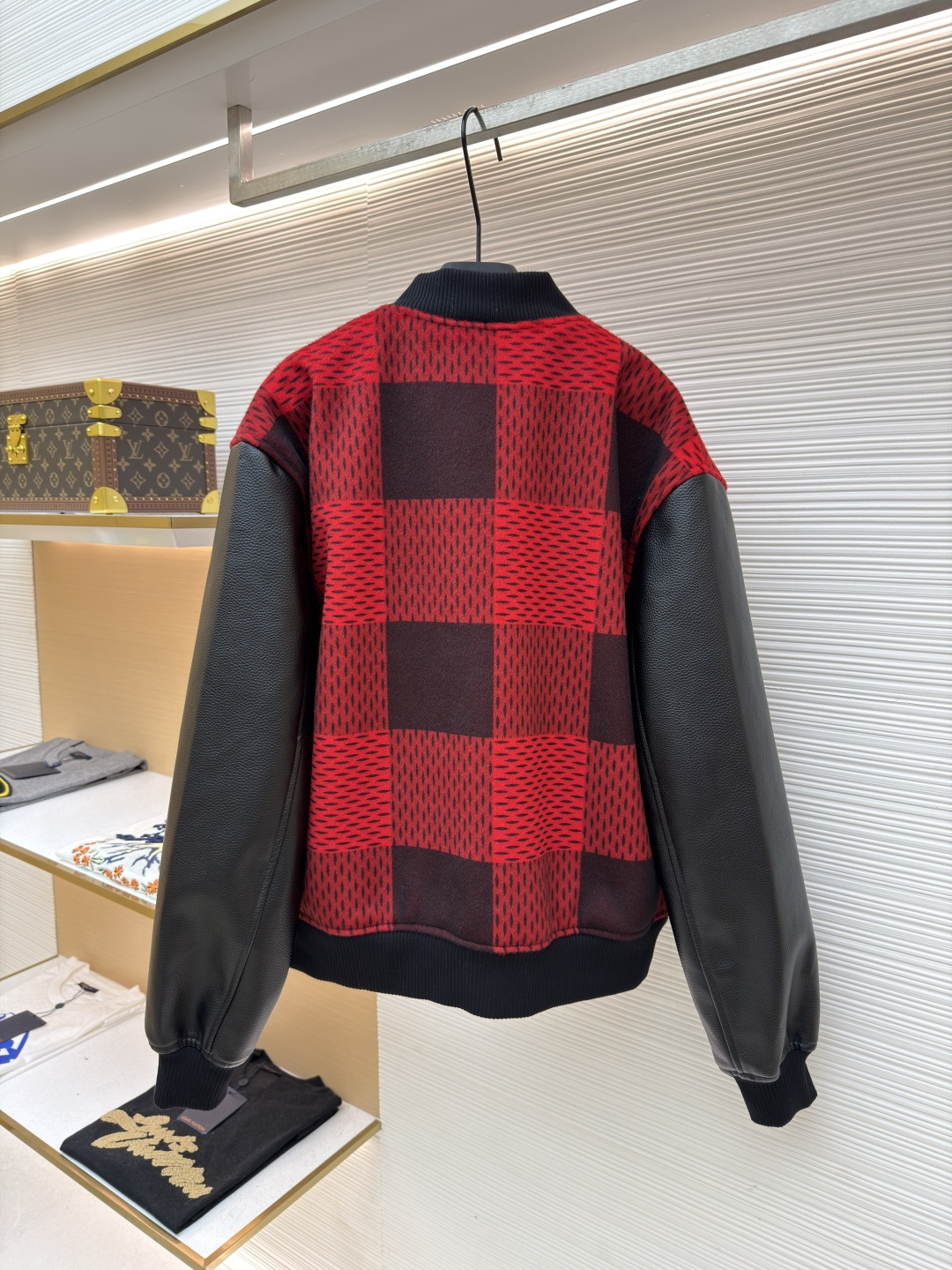 P330 LOUIS VUITTON 格纹Logo字母串珠刺绣夹克
●原版：45646购入开发
●货号：1681758-B95
●面料：羊毛混纺面料
●工艺：串珠刺绣制作
●颜色：红黑格子
●版型：合身版型
●克重：约1250克
●尺码：46-48-50-52
●描述：主体采用撞色格纹针织面料，通过提花编织工艺打造纹理层次，触感柔软且版型挺括；袖子拼接哑光皮革材质，经防刮耐磨处理，兼具质感与耐用性。衣身装饰品牌字母标识，采用立体绣线工艺，色彩鲜明且纹理清晰，强化辨识度。版型为合身棒球领设计，搭配珍珠纽扣开合，穿脱便捷；罗纹领口、袖口及下摆增强贴合度，兼顾防风性与休闲感。全衣拼接处采用精密锁边工艺，无外露线头，手工测量尺寸（误差1-3CM属正常），工艺平衡了针织的柔和与皮革的硬朗，呈现品牌潮流高级风格。整体走线平直细腻，面料舒适柔软，颜色一致无色差 能与同款搭配营造时尚造型，驾驭各种场合，定制辅料，三标齐全，男女同款！