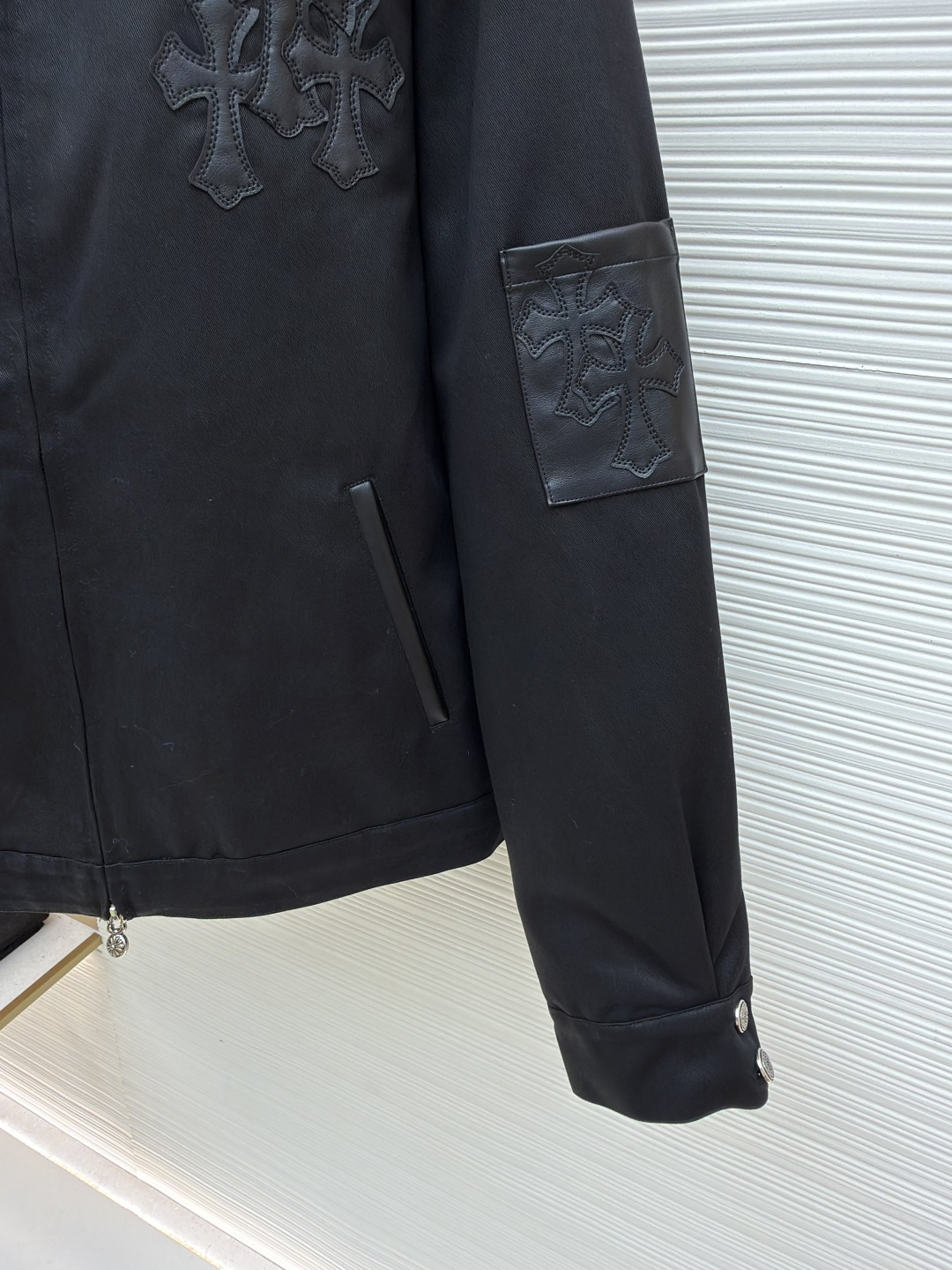 P310 Chrome Hearts 纯色Logo贴标翻领夹克
●原版：13730购入开发
●货号：1681764-B75
●面料：皮革面料
●工艺：贴布制作
●颜色：黑色
●版型：合身版型
●克重：约1020克
●尺码：S-M-L-XL
●描述：采用高密哑光面料，经防皱定型工艺处理，兼具挺括度与垂坠质感，触感顺滑且不易起球。衣身装饰品牌标志性十字刺绣，通过立体绗绣工艺打造，图案层次饱满、纹理清晰，兼具辨识度与精致度；袖口拼接皮质贴标，经热压贴合工艺固定，增强质感与耐用性。版型为宽松剪裁，搭配金属拉链+装饰吊坠，穿脱便捷且提升细节亮点；袖口纽扣调节设计适配不同臂围，下摆自然收边保障版型利落。全衣缝线工整，拼接处无外露线头，手工测量尺寸（误差1-3CM属正常），工艺平衡了暗黑风格与实穿属性，是兼具造型感与实用性的单品。整体走线平直细腻，面料舒适柔软，颜色一致无色差 能与同款搭配营造时尚造型，驾驭各种场合，定制辅料，三标齐全，男女同款！