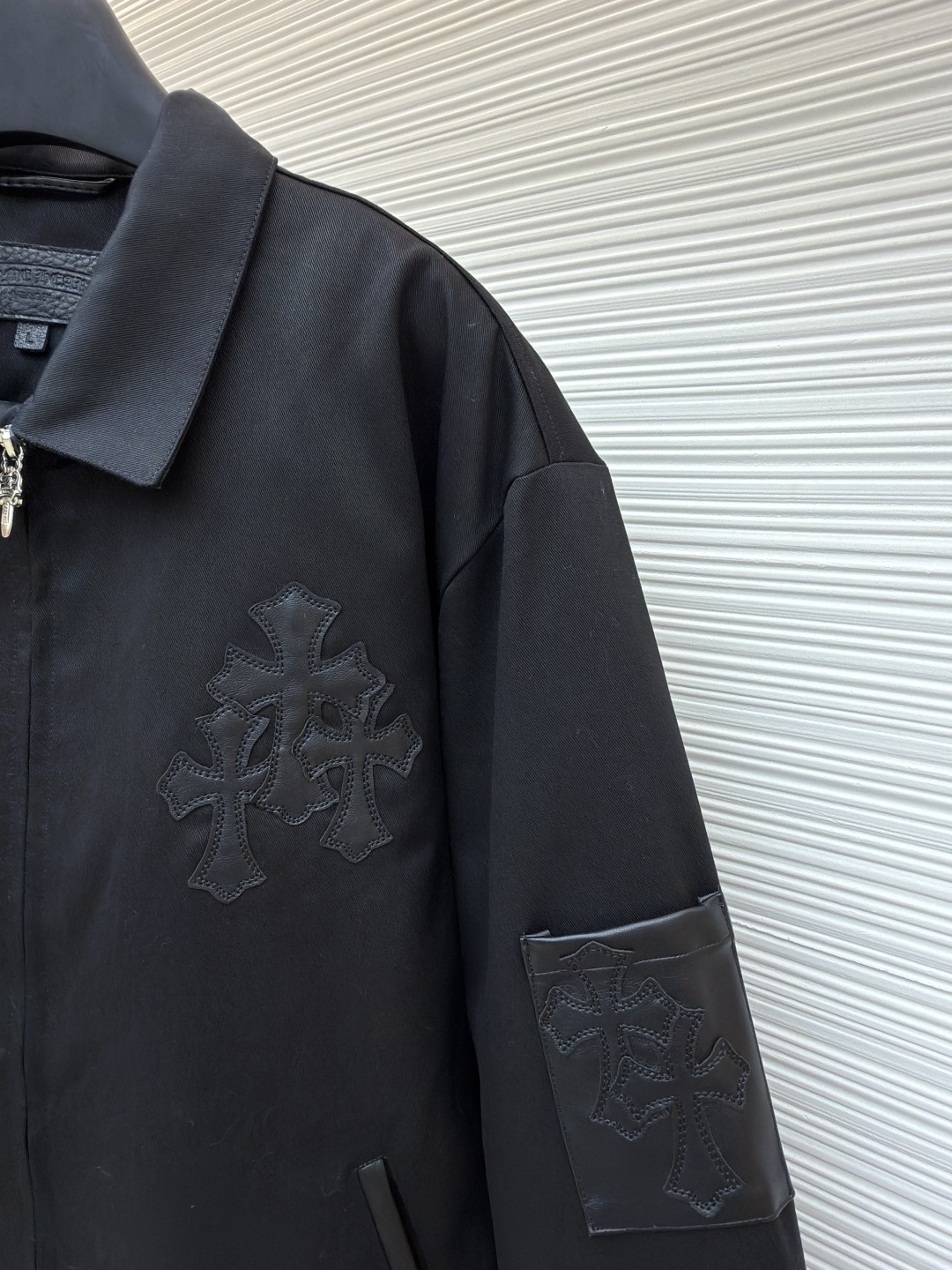 P310 Chrome Hearts 纯色Logo贴标翻领夹克
●原版：13730购入开发
●货号：1681764-B75
●面料：皮革面料
●工艺：贴布制作
●颜色：黑色
●版型：合身版型
●克重：约1020克
●尺码：S-M-L-XL
●描述：采用高密哑光面料，经防皱定型工艺处理，兼具挺括度与垂坠质感，触感顺滑且不易起球。衣身装饰品牌标志性十字刺绣，通过立体绗绣工艺打造，图案层次饱满、纹理清晰，兼具辨识度与精致度；袖口拼接皮质贴标，经热压贴合工艺固定，增强质感与耐用性。版型为宽松剪裁，搭配金属拉链+装饰吊坠，穿脱便捷且提升细节亮点；袖口纽扣调节设计适配不同臂围，下摆自然收边保障版型利落。全衣缝线工整，拼接处无外露线头，手工测量尺寸（误差1-3CM属正常），工艺平衡了暗黑风格与实穿属性，是兼具造型感与实用性的单品。整体走线平直细腻，面料舒适柔软，颜色一致无色差 能与同款搭配营造时尚造型，驾驭各种场合，定制辅料，三标齐全，男女同款！