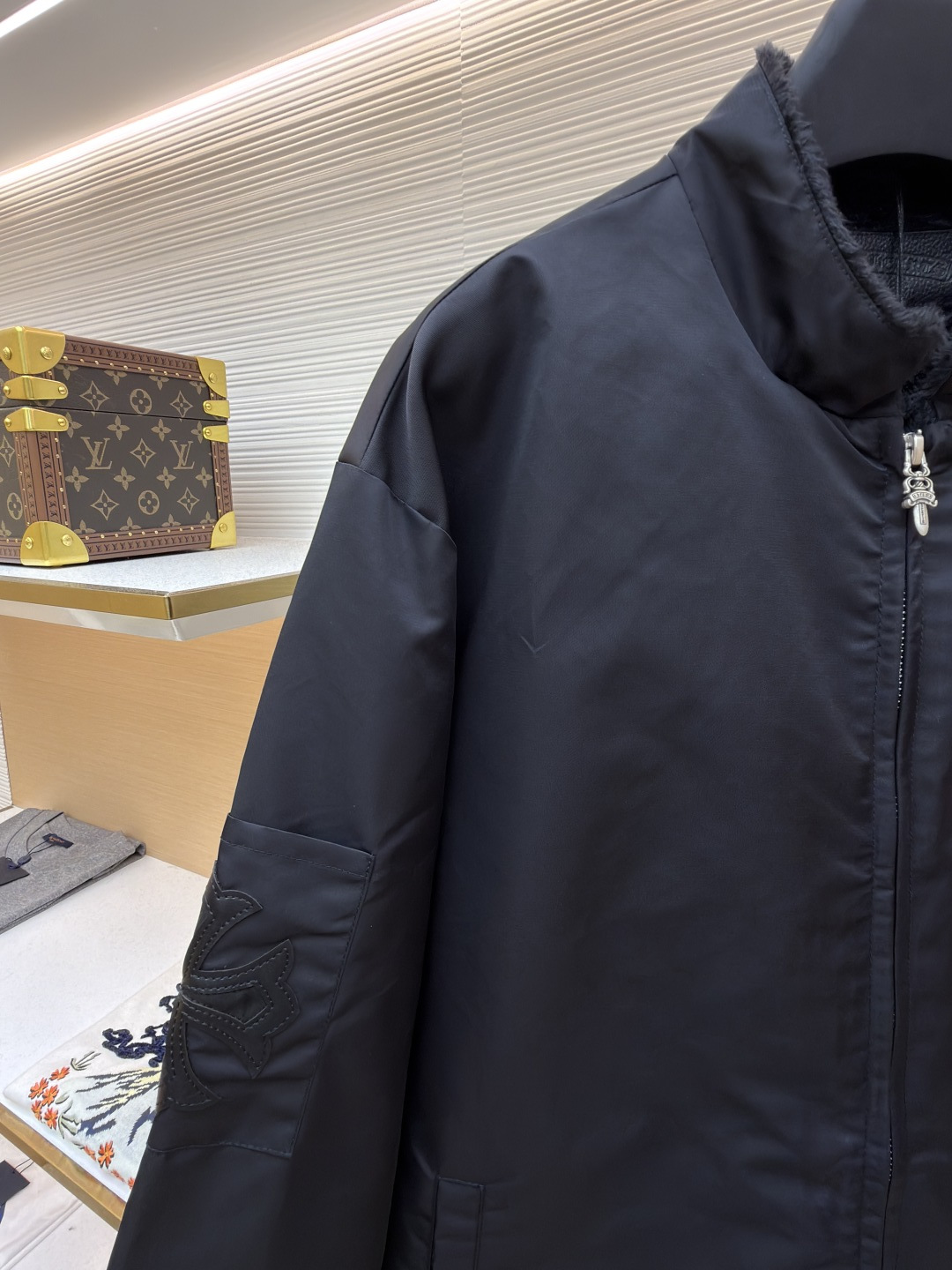 P295 Chrome Hearts 贴布条纹夹克
●原版：30000购入开发
●货号：1681765-B60
●面料：聚酯纤维面料
●工艺：贴布制作
●颜色：黑色
●版型：合身版型
●克重：约680克
●尺码：S-M-L-XL
●描述：采用高密防风面料，经防泼水涂层处理，兼具耐用性与防护性，触感顺滑且不易起皱。衣身侧边拼接黑白条纹装饰，通过精准定位缝制工艺固定，线条规整增强视觉层次；正面装饰品牌红色Logo印花，采用高温烫印工艺，色彩饱和且不易脱落，凸显辨识度。版型为宽松剪裁，搭配金属拉链开合，穿脱便捷；罗纹领口、袖口及下摆增强贴合度，兼顾防风性与休闲感。全衣缝线工整，拼接处无外露线头，手工测量尺寸（误差1-3CM属正常），工艺平衡了街头风格与品牌标志性设计，是兼具实穿性与潮流感的单品。整体走线平直细腻，面料舒适柔软，颜色一致无色差 能与同款搭配营造时尚造型，驾驭各种场合，定制辅料，三标齐全，男女同款！