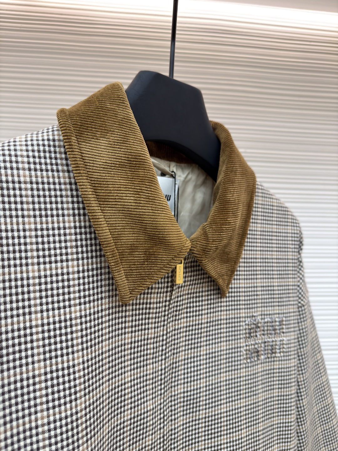 P285 MIU MIU千鸟格拼色外套
●原版：10329购入开发
●货号：1681768-B50
●面料：全棉面料
●工艺：压印制作
●版型：合身版型
●克重：约725克
●尺码：36-38-40-42
●描述：采用千鸟格混纺面料，经预缩定型工艺处理，保障版型挺括且不易变形，触感柔软兼具质感。领口拼接灯芯绒材质，通过恒温复合工艺固定，纹理饱满增强复古氛围；衣身装饰品牌暗纹标识，采用压印工艺打造，低调精致且辨识度高。版型为宽松剪裁，适配多元身形，搭配拉链+纽扣双重开合，穿脱便捷；下摆抽绳设计可调节版型，袖口简约收边兼顾利落感。全衣缝线工整，拼接处无外露线头，手工测量尺寸（误差1-3CM属正常），工艺平衡了复古格纹与甜酷风格，是兼具实穿性与造型感的单品。整体走线平直细腻，面料舒适柔软，颜色一致无色差 能与同款搭配营造时尚造型，驾驭各种场合，定制辅料，三标齐全，男女同款！