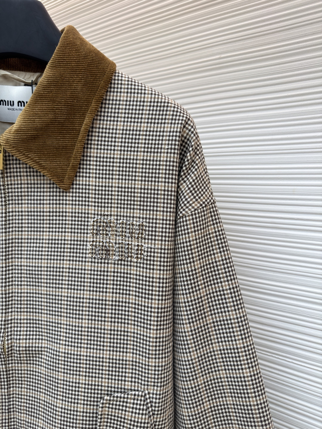 P285 MIU MIU千鸟格拼色外套
●原版：10329购入开发
●货号：1681768-B50
●面料：全棉面料
●工艺：压印制作
●版型：合身版型
●克重：约725克
●尺码：36-38-40-42
●描述：采用千鸟格混纺面料，经预缩定型工艺处理，保障版型挺括且不易变形，触感柔软兼具质感。领口拼接灯芯绒材质，通过恒温复合工艺固定，纹理饱满增强复古氛围；衣身装饰品牌暗纹标识，采用压印工艺打造，低调精致且辨识度高。版型为宽松剪裁，适配多元身形，搭配拉链+纽扣双重开合，穿脱便捷；下摆抽绳设计可调节版型，袖口简约收边兼顾利落感。全衣缝线工整，拼接处无外露线头，手工测量尺寸（误差1-3CM属正常），工艺平衡了复古格纹与甜酷风格，是兼具实穿性与造型感的单品。整体走线平直细腻，面料舒适柔软，颜色一致无色差 能与同款搭配营造时尚造型，驾驭各种场合，定制辅料，三标齐全，男女同款！