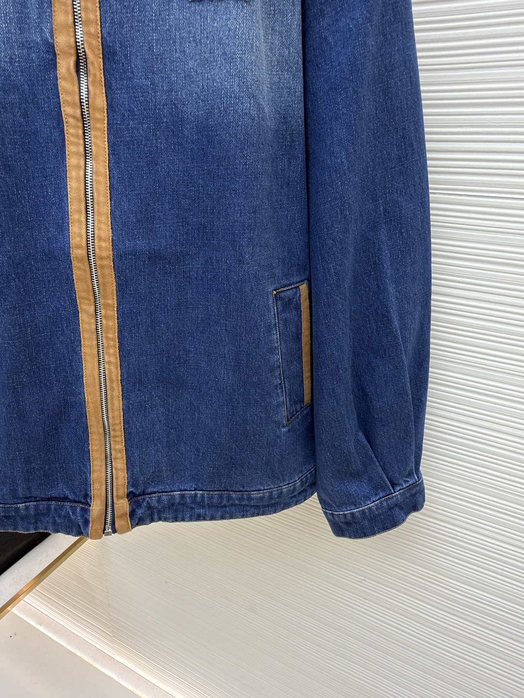 P280 MIU MIU皮革饰边牛仔外套 
●原版：16708购入开发
●货号：1681771-B45
●面料：牛仔面料
●工艺：立体绣线制作
●颜色：蓝色
●版型：合身版型
●克重：约1085克
●尺码：S-M-L
●描述：采用做旧水洗牛仔面料，经石磨工艺处理，呈现自然渐变色泽，触感柔软且保留牛仔挺括质感。衣身拼接棕褐色皮质饰条，通过精密车缝工艺固定，纹理细腻增强复古层次；胸前装饰品牌字母刺绣，采用立体绣线工艺，线条清晰且不易脱落，凸显辨识度。版型为宽松剪裁，适配多元身形，拉链开合搭配翻领设计，穿脱便捷且适配多场景；袖口、下摆采用牛仔原边收缝，保障版型利落度。全衣缝线工整，拼接处无外露线头，手工测量尺寸（误差1-3CM属正常），工艺平衡了复古牛仔与甜酷风格，是兼具实穿性与造型感的单品。整体走线平直细腻，面料舒适柔软，颜色一致无色差 能与同款搭配营造时尚造型，驾驭各种场合，定制辅料，三标齐全，男女同款！