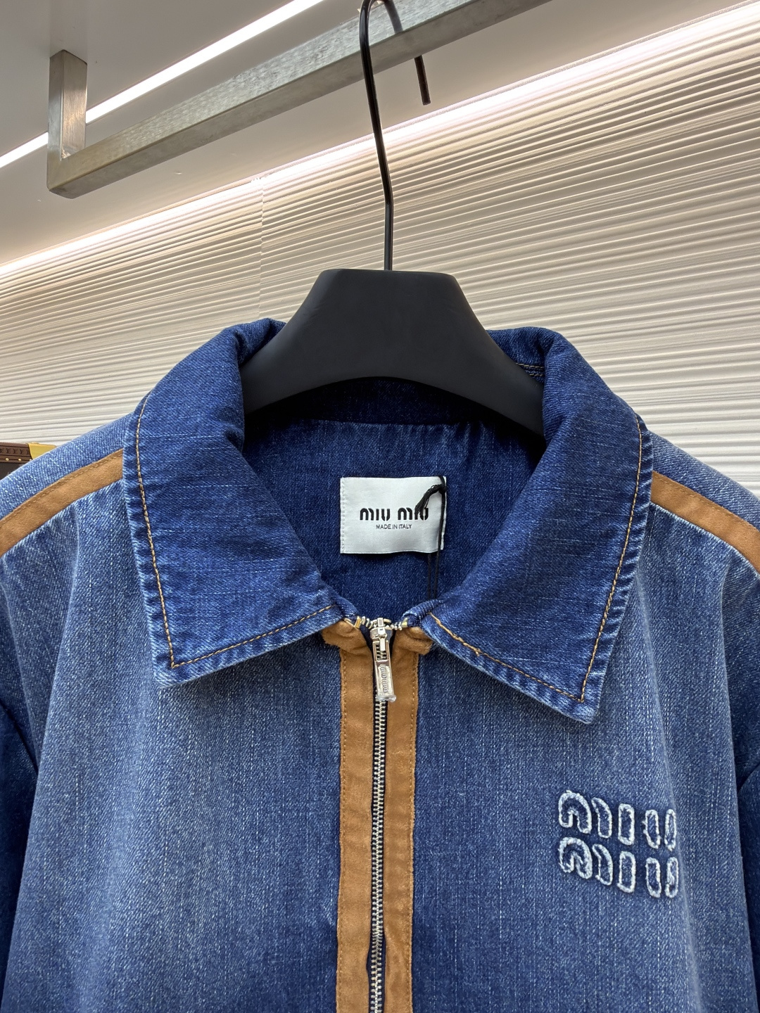 P280 MIU MIU皮革饰边牛仔外套 
●原版：16708购入开发
●货号：1681771-B45
●面料：牛仔面料
●工艺：立体绣线制作
●颜色：蓝色
●版型：合身版型
●克重：约1085克
●尺码：S-M-L
●描述：采用做旧水洗牛仔面料，经石磨工艺处理，呈现自然渐变色泽，触感柔软且保留牛仔挺括质感。衣身拼接棕褐色皮质饰条，通过精密车缝工艺固定，纹理细腻增强复古层次；胸前装饰品牌字母刺绣，采用立体绣线工艺，线条清晰且不易脱落，凸显辨识度。版型为宽松剪裁，适配多元身形，拉链开合搭配翻领设计，穿脱便捷且适配多场景；袖口、下摆采用牛仔原边收缝，保障版型利落度。全衣缝线工整，拼接处无外露线头，手工测量尺寸（误差1-3CM属正常），工艺平衡了复古牛仔与甜酷风格，是兼具实穿性与造型感的单品。整体走线平直细腻，面料舒适柔软，颜色一致无色差 能与同款搭配营造时尚造型，驾驭各种场合，定制辅料，三标齐全，男女同款！