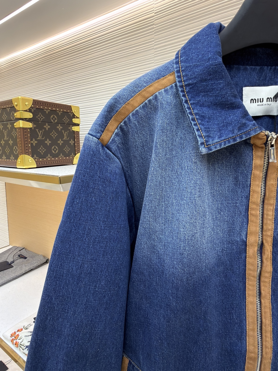 P280 MIU MIU皮革饰边牛仔外套 
●原版：16708购入开发
●货号：1681771-B45
●面料：牛仔面料
●工艺：立体绣线制作
●颜色：蓝色
●版型：合身版型
●克重：约1085克
●尺码：S-M-L
●描述：采用做旧水洗牛仔面料，经石磨工艺处理，呈现自然渐变色泽，触感柔软且保留牛仔挺括质感。衣身拼接棕褐色皮质饰条，通过精密车缝工艺固定，纹理细腻增强复古层次；胸前装饰品牌字母刺绣，采用立体绣线工艺，线条清晰且不易脱落，凸显辨识度。版型为宽松剪裁，适配多元身形，拉链开合搭配翻领设计，穿脱便捷且适配多场景；袖口、下摆采用牛仔原边收缝，保障版型利落度。全衣缝线工整，拼接处无外露线头，手工测量尺寸（误差1-3CM属正常），工艺平衡了复古牛仔与甜酷风格，是兼具实穿性与造型感的单品。整体走线平直细腻，面料舒适柔软，颜色一致无色差 能与同款搭配营造时尚造型，驾驭各种场合，定制辅料，三标齐全，男女同款！