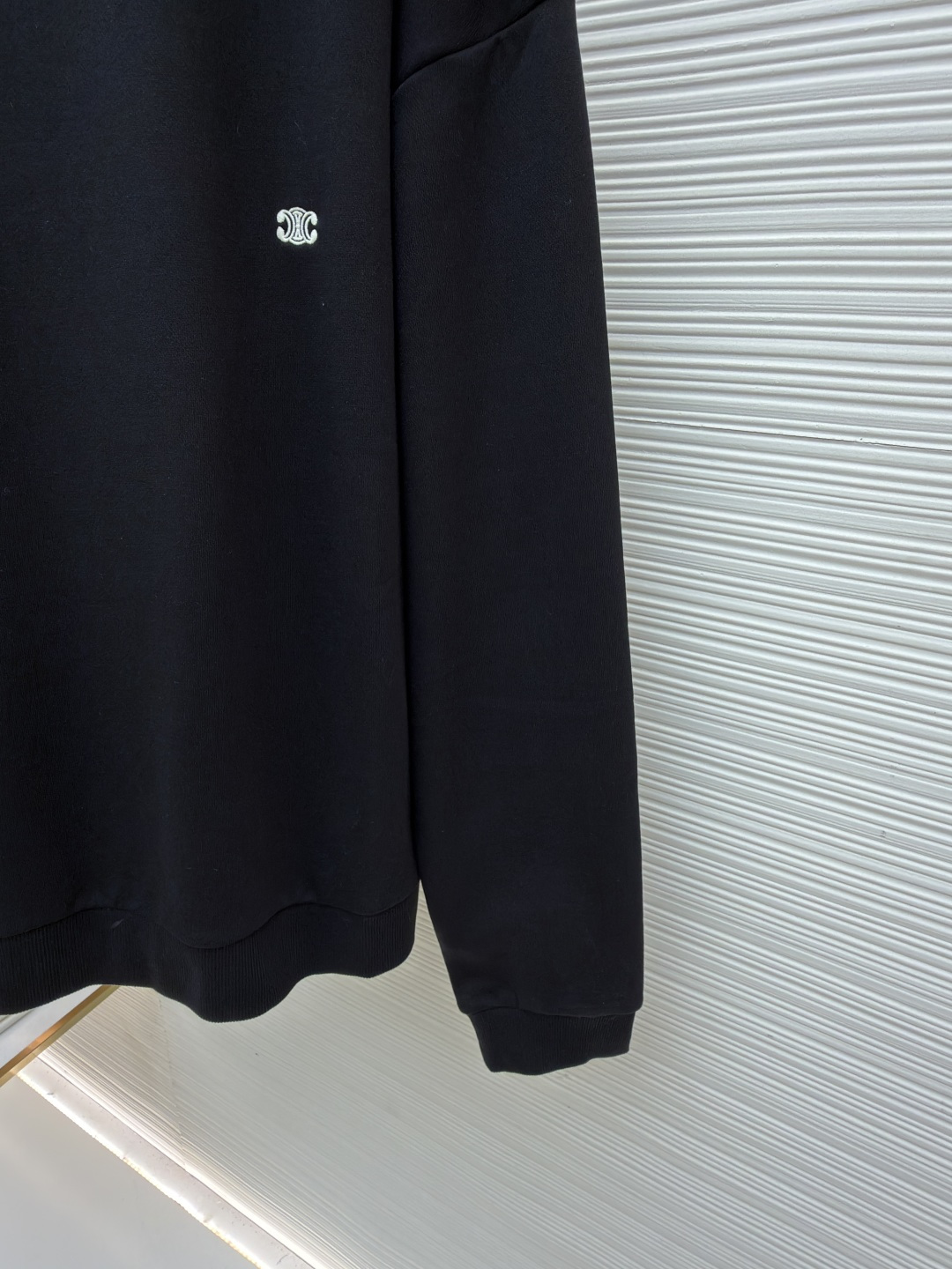 P165 Celine  凯旋门刺绣卫衣
●原版：8300购入开发
●货号：1682044-A35
●面料：全棉臻柔活性墨韵卫衣面料
●工艺：刺绣制作
●颜色：黑色
●版型：合身版型
●克重：约545克
●尺码：S-M-L-XL
●描述：定制全棉臻柔活性墨韵卫衣料 手感柔软 舒适亲肤 以一抹深邃黑幕为底 胸前悄然绘就一方三角形天地 标志性Celine 凯旋门标识点缀正面 以极致的简约勾勒出高级的轮廓  成为视觉的灵动焦点  于无声处彰显品味。采用进口机刺绣工艺 使用先进的计算机控制系统和精密的机械部件 实现凯旋门刺绣作业  精度高 线条流畅而细腻，面料都经过浇洗 手感质感更佳 不易变形 不易缩水 不易褪色 保持长久的美观。整体走线平直细腻，面料舒适柔软，颜色一致无色差 能与同款搭配营造时尚造型，驾驭各种场合，定制辅料，三标齐全，男女同款！