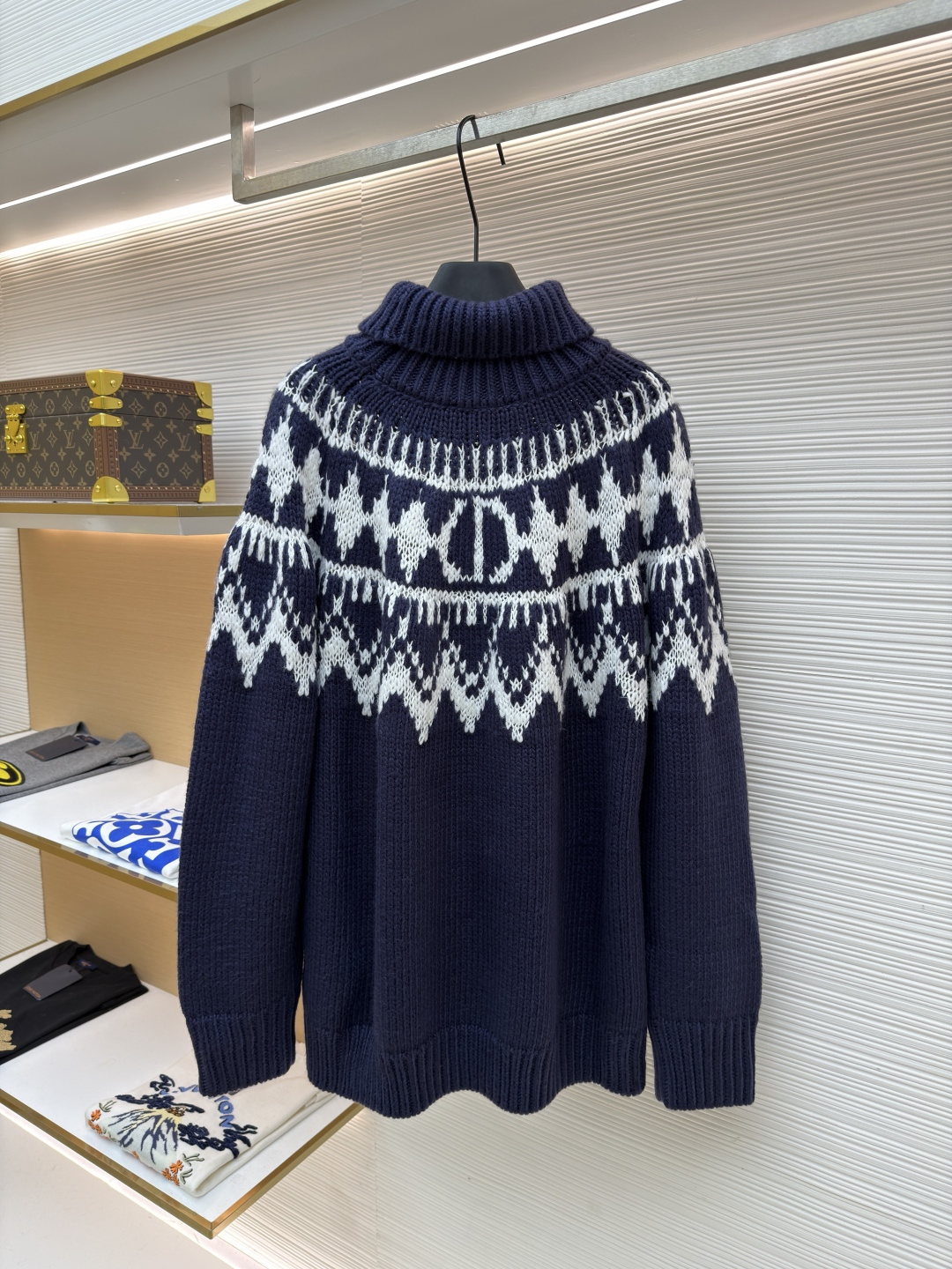 P250 Dior 提花高领毛衣
●原版：18000购入开发
●货号：1682045-B20
●面料：羊毛面料
●工艺：提花针织制作
●颜色：蓝白
●版型：合身版型
●克重：约1055克
●尺码：S-M-L-XL
●描述：定织雅绒蓝白绵羊毛针织锦 质感十足 厚重扎实 每一寸纤维都蕴含着沉甸甸的暖意 当这抹深邃的蓝遇上纯净的白色 纯净而优雅 饰以灵感源自冬季运动世界的 Fair Isle 图案点缀其间 带着一种冬日独有的静谧与诗意 精致的几何纹路营造出一种神秘而优雅的氛围 背面精心饰以的CD标志 宛如时尚殿堂的徽章 奢华的象征 与生俱来的高贵气质 让每一个瞬间都散发出典雅与时尚交织的迷人魅。德国进口机提花组织而成 精确地控制纱线的排列和交织方式 在织机上精心交织  Fair Isle图案以及CD 提花艺术图案镶饰 织物更加生动立体，曲型螺纹组织 通过改变针织过程中的针法和纱线的排列方式 使纱线在织物中呈现出曲线状的分布，成衣洗水加软去味工艺 通过专业的洗涤设备和特定的洗涤剂 对衣物进行深度清洁和去味处理 改善衣物的手感和外观。整体走线平直细腻，面料舒适柔软，颜色一致无色差 能与同款搭配营造时尚造型，驾驭各种场合，定制辅料，三标齐全，男女同款！