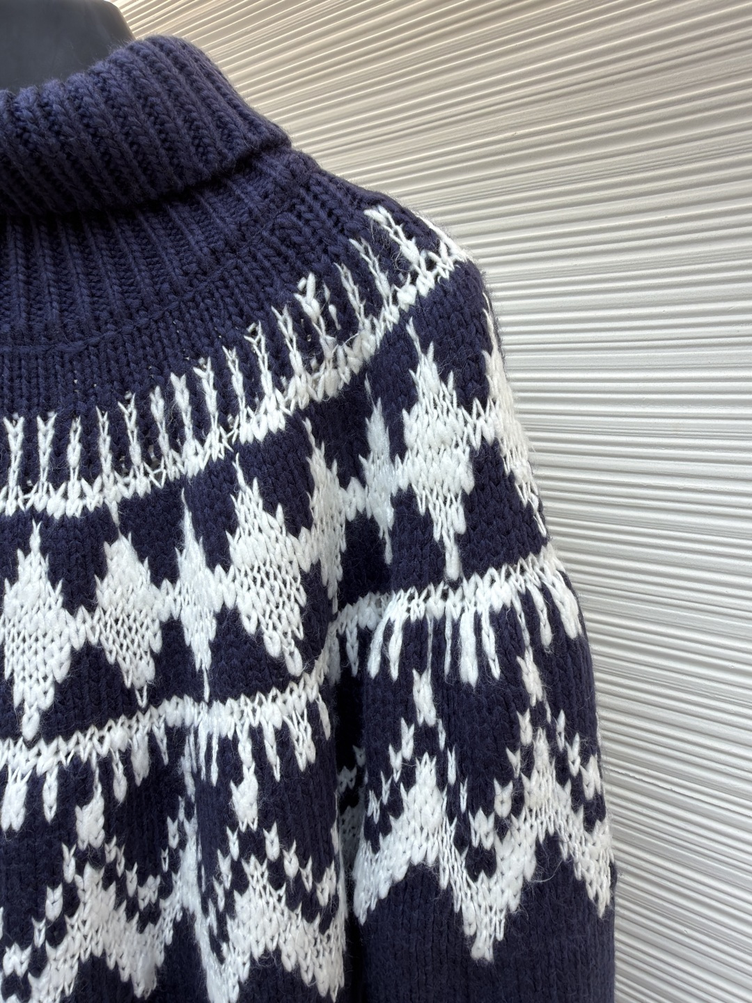 P250 Dior 提花高领毛衣
●原版：18000购入开发
●货号：1682045-B20
●面料：羊毛面料
●工艺：提花针织制作
●颜色：蓝白
●版型：合身版型
●克重：约1055克
●尺码：S-M-L-XL
●描述：定织雅绒蓝白绵羊毛针织锦 质感十足 厚重扎实 每一寸纤维都蕴含着沉甸甸的暖意 当这抹深邃的蓝遇上纯净的白色 纯净而优雅 饰以灵感源自冬季运动世界的 Fair Isle 图案点缀其间 带着一种冬日独有的静谧与诗意 精致的几何纹路营造出一种神秘而优雅的氛围 背面精心饰以的CD标志 宛如时尚殿堂的徽章 奢华的象征 与生俱来的高贵气质 让每一个瞬间都散发出典雅与时尚交织的迷人魅。德国进口机提花组织而成 精确地控制纱线的排列和交织方式 在织机上精心交织  Fair Isle图案以及CD 提花艺术图案镶饰 织物更加生动立体，曲型螺纹组织 通过改变针织过程中的针法和纱线的排列方式 使纱线在织物中呈现出曲线状的分布，成衣洗水加软去味工艺 通过专业的洗涤设备和特定的洗涤剂 对衣物进行深度清洁和去味处理 改善衣物的手感和外观。整体走线平直细腻，面料舒适柔软，颜色一致无色差 能与同款搭配营造时尚造型，驾驭各种场合，定制辅料，三标齐全，男女同款！