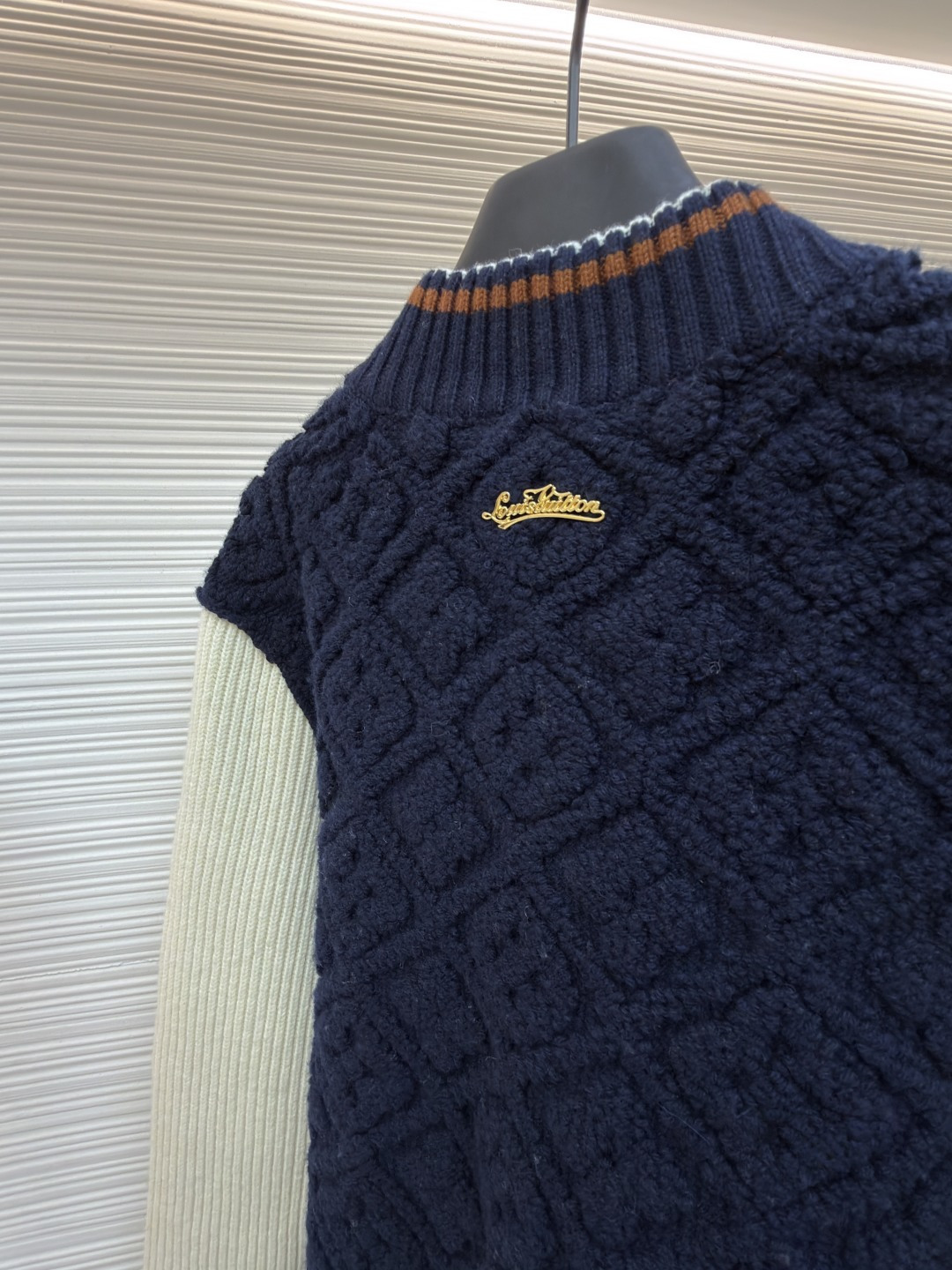 P815 LOUIS VUITTON SKI滑雪系列拼色条纹棒球长袖外套
●原版：22999购入开发
●面料：羊毛混纺面料
●工艺：针织制作
●颜色：蓝白
●版型：合身版型
●克重：约1070克
●尺码：XS-S-M-L
●描述：这款路易威登拼色针织开衫采用立体绞花编织工艺打造主体衣身，选用高支数美利奴羊毛混纺面料，通过双针床针织机织造出凹凸有致的菱格纹理，每平方厘米编织密度达32针，让纹理兼具立体感与柔软度；衣身主体为藏青色定纺纱线，经三次水洗固色处理，有效防止褪色。袖子部分采用米白色竖坑条罗纹针织，单股纱线捻度控制在800捻/米，保证回弹性与贴合度。金属按扣为定制黄铜材质，经镀金封釉工艺处理；领口、下摆的撞色罗纹采用嵌花编织，精准对接品牌经典三色织带比例，袖口处还暗藏激光雕刻的品牌标识，整体工艺融合传统针织技法与现代精工，细节处尽显匠造水准。整体走线平直细腻，面料舒适柔软，颜色一致无色差 能与同款搭配营造时尚造型，驾驭各种场合，定制辅料，三标齐全，男女同款！