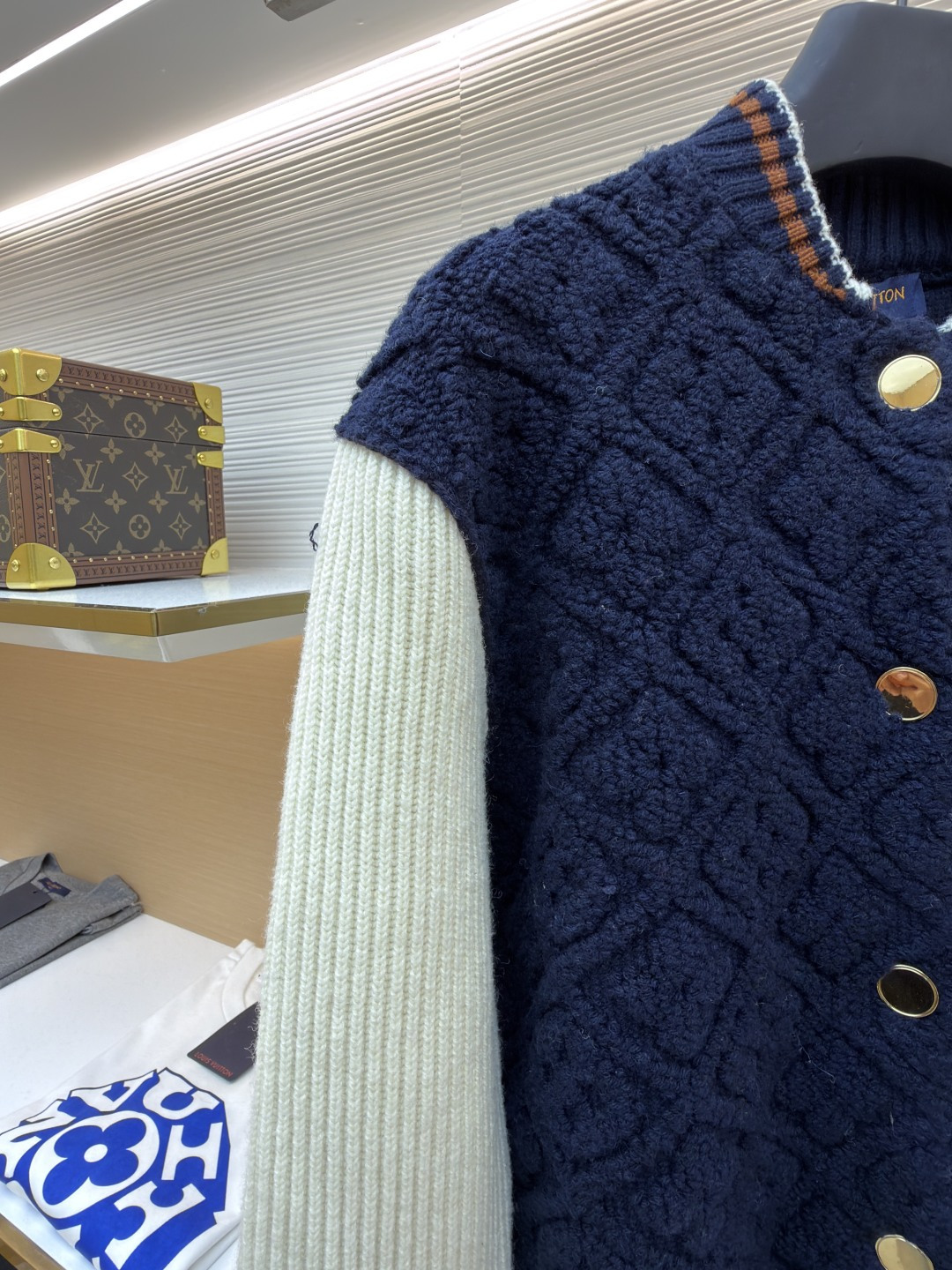 P815 LOUIS VUITTON SKI滑雪系列拼色条纹棒球长袖外套
●原版：22999购入开发
●面料：羊毛混纺面料
●工艺：针织制作
●颜色：蓝白
●版型：合身版型
●克重：约1070克
●尺码：XS-S-M-L
●描述：这款路易威登拼色针织开衫采用立体绞花编织工艺打造主体衣身，选用高支数美利奴羊毛混纺面料，通过双针床针织机织造出凹凸有致的菱格纹理，每平方厘米编织密度达32针，让纹理兼具立体感与柔软度；衣身主体为藏青色定纺纱线，经三次水洗固色处理，有效防止褪色。袖子部分采用米白色竖坑条罗纹针织，单股纱线捻度控制在800捻/米，保证回弹性与贴合度。金属按扣为定制黄铜材质，经镀金封釉工艺处理；领口、下摆的撞色罗纹采用嵌花编织，精准对接品牌经典三色织带比例，袖口处还暗藏激光雕刻的品牌标识，整体工艺融合传统针织技法与现代精工，细节处尽显匠造水准。整体走线平直细腻，面料舒适柔软，颜色一致无色差 能与同款搭配营造时尚造型，驾驭各种场合，定制辅料，三标齐全，男女同款！