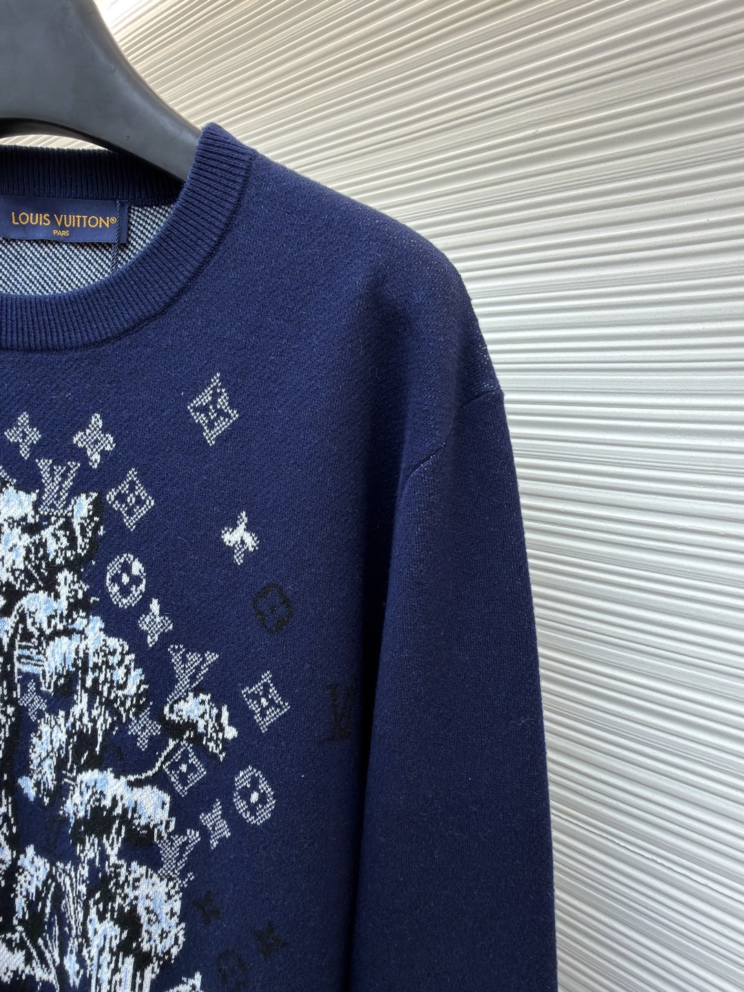 P275 LOUIS VUITTON 马年限定嵌花字母提花针织毛衣
●货号：1682611-B40
●面料：羊毛面料
●工艺：提花针织制作
●颜色：藏蓝色
●版型：合身版型
●克重：约430克
●尺码：S-M-L-XL
●描述：这款LOUIS VUITTON藏青色圆领针织衫甄选高品质羊毛混纺纱线打造，经预缩水处理后触感柔软亲肤，兼具良好的透气性与保暖性，不易起球、变形、褪色，藏青色调沉稳大气且富有质感。衣身中央的植物花卉图案采用嵌花提花工艺织造，纹理立体饱满，搭配环绕四周的品牌经典Monogram标识，通过色织工艺呈现细腻层次，视觉效果精致且富有辨识度。经典圆领采用双针加固包边，耐穿不易松垮，袖口与下摆为同色系罗纹收边，弹性适中贴合身形，整体为宽松合身廓形，肩部无缝拼接走线平直，锁边工艺精致，定制辅料与品牌标识细节齐全，适配日常休闲、轻商务等多种穿搭场景，是打造简约高级造型的时尚单品。整体走线平直细腻，面料舒适柔软，颜色一致无色差 能与同款搭配营造时尚造型，驾驭各种场合，定制辅料，三标齐全，男女同款！