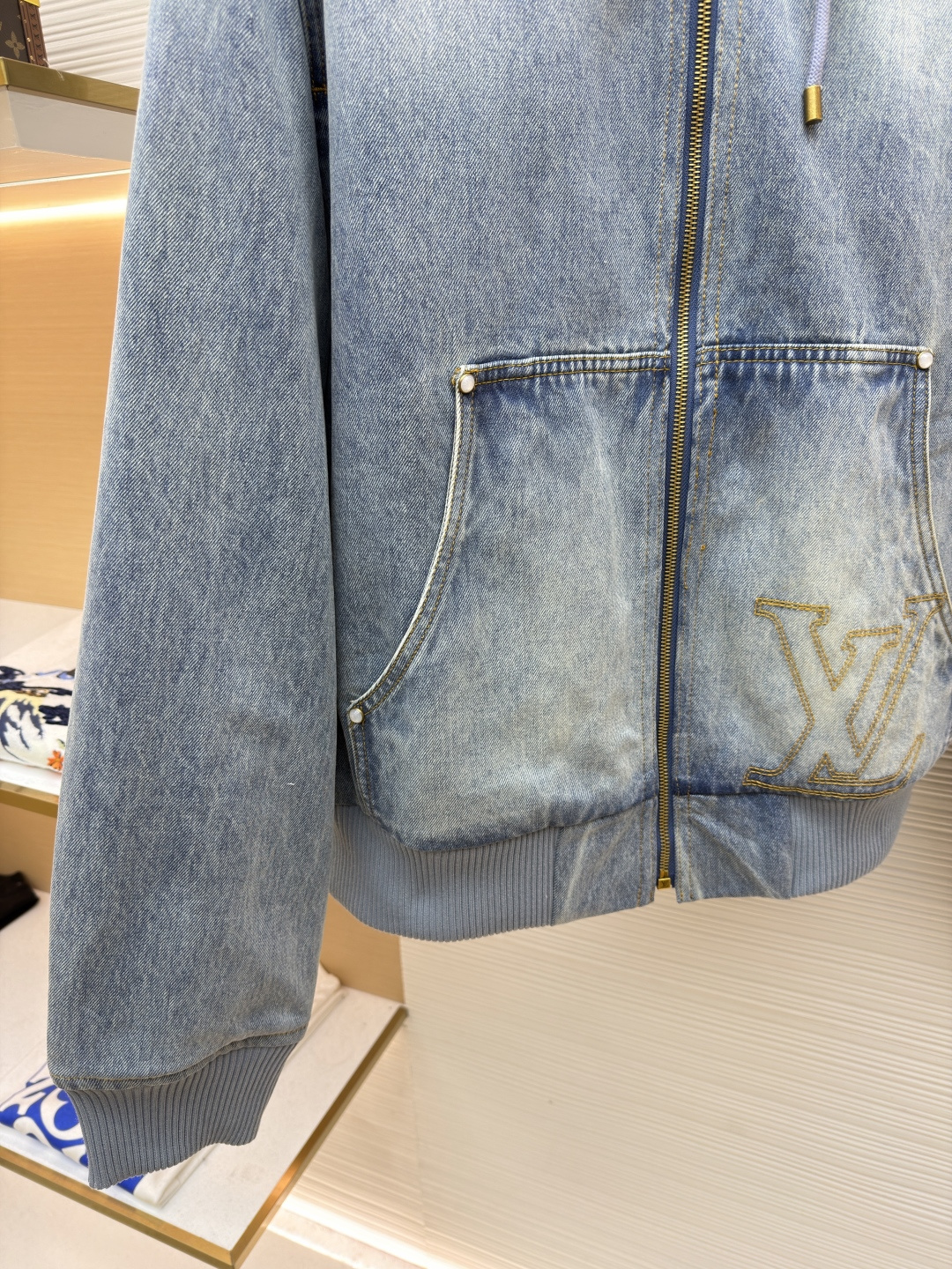 P360 LOUIS VUITTON 口袋字母刺绣连帽牛仔外套
●原版：21579购入开发
●货号：1682616-C25
●面料：牛仔面料
●工艺：刺绣制作
●颜色：洗水蓝
●版型：合身版型
●克重：约1390克
●尺码：46-48-50-52
●描述：这件LOUIS VUITTON连帽抽绳拉链徽标刺绣工装长袖牛仔外套，选用重磅复古水洗牛仔布打造，经过多道酵洗与石磨工艺，呈现自然柔和的浅蓝褪色效果与细腻做旧纹理。外套采用宽松落肩版型，搭配罗纹收边袖口与下摆，兼顾复古工装感与日常穿着舒适度。连帽设计配备同色系抽绳，金属拉链头镌刻品牌标识，前幅立体贴袋处饰有低调的LV刺绣徽标，袋口以金属铆钉加固，兼具装饰性与耐用性。内里采用格纹棉质面料提升穿着体验，每一处缝线都经过精细处理，既保留了牛仔的硬朗质感，又融入了LV标志性的精致细节，是打造随性街头造型的高阶选择。整体走线平直细腻，面料舒适柔软，颜色一致无色差 能与同款搭配营造时尚造型，驾驭各种场合，定制辅料，三标齐全，男女同款！