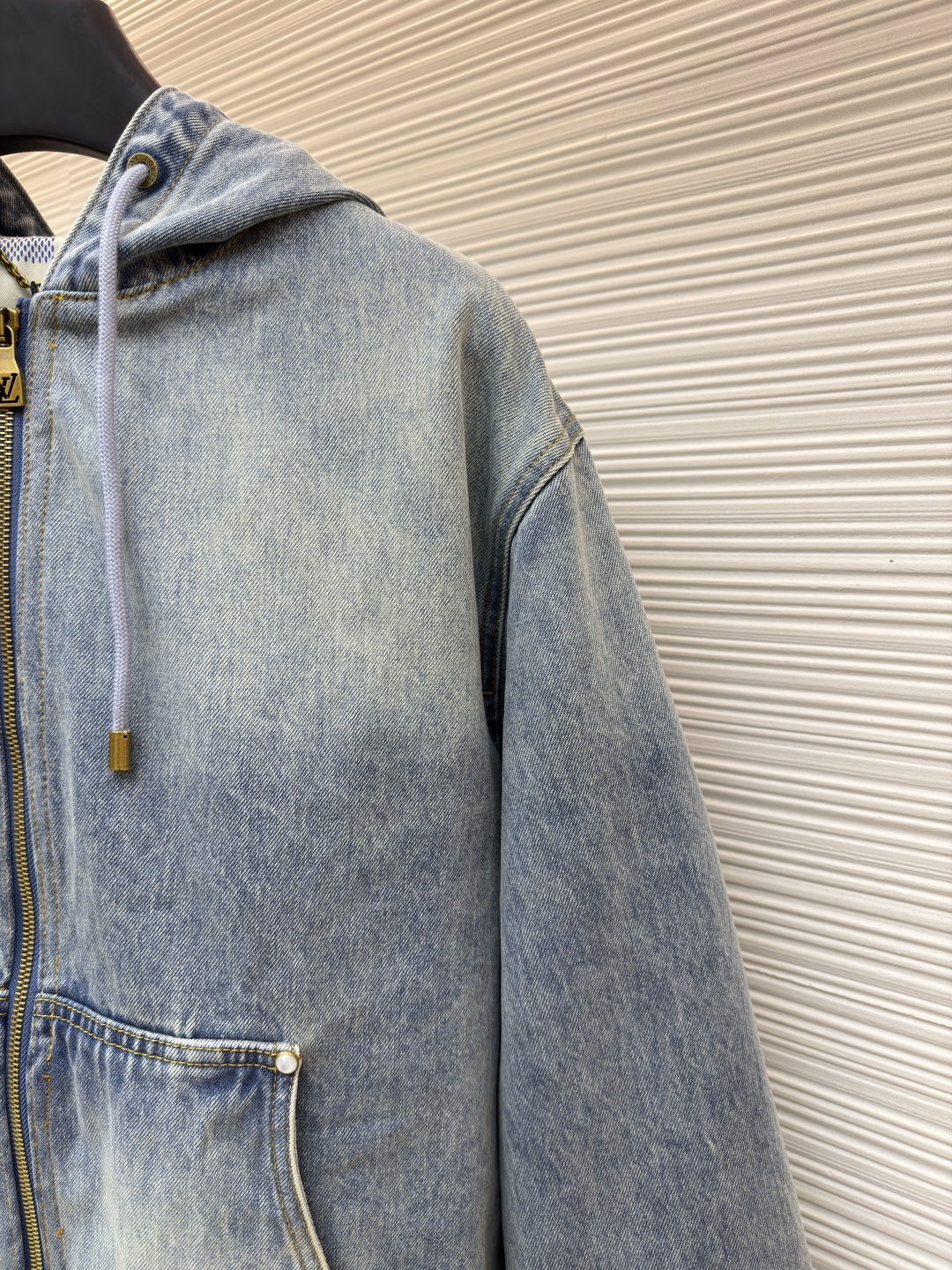 P360 LOUIS VUITTON 口袋字母刺绣连帽牛仔外套
●原版：21579购入开发
●货号：1682616-C25
●面料：牛仔面料
●工艺：刺绣制作
●颜色：洗水蓝
●版型：合身版型
●克重：约1390克
●尺码：46-48-50-52
●描述：这件LOUIS VUITTON连帽抽绳拉链徽标刺绣工装长袖牛仔外套，选用重磅复古水洗牛仔布打造，经过多道酵洗与石磨工艺，呈现自然柔和的浅蓝褪色效果与细腻做旧纹理。外套采用宽松落肩版型，搭配罗纹收边袖口与下摆，兼顾复古工装感与日常穿着舒适度。连帽设计配备同色系抽绳，金属拉链头镌刻品牌标识，前幅立体贴袋处饰有低调的LV刺绣徽标，袋口以金属铆钉加固，兼具装饰性与耐用性。内里采用格纹棉质面料提升穿着体验，每一处缝线都经过精细处理，既保留了牛仔的硬朗质感，又融入了LV标志性的精致细节，是打造随性街头造型的高阶选择。整体走线平直细腻，面料舒适柔软，颜色一致无色差 能与同款搭配营造时尚造型，驾驭各种场合，定制辅料，三标齐全，男女同款！