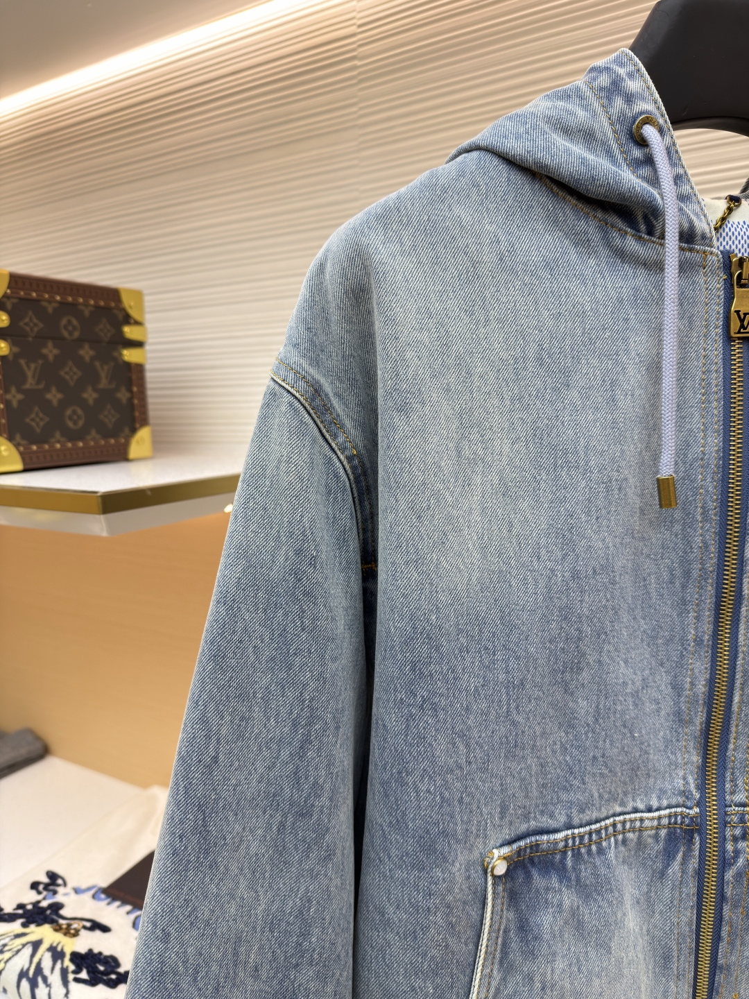P360 LOUIS VUITTON 口袋字母刺绣连帽牛仔外套
●原版：21579购入开发
●货号：1682616-C25
●面料：牛仔面料
●工艺：刺绣制作
●颜色：洗水蓝
●版型：合身版型
●克重：约1390克
●尺码：46-48-50-52
●描述：这件LOUIS VUITTON连帽抽绳拉链徽标刺绣工装长袖牛仔外套，选用重磅复古水洗牛仔布打造，经过多道酵洗与石磨工艺，呈现自然柔和的浅蓝褪色效果与细腻做旧纹理。外套采用宽松落肩版型，搭配罗纹收边袖口与下摆，兼顾复古工装感与日常穿着舒适度。连帽设计配备同色系抽绳，金属拉链头镌刻品牌标识，前幅立体贴袋处饰有低调的LV刺绣徽标，袋口以金属铆钉加固，兼具装饰性与耐用性。内里采用格纹棉质面料提升穿着体验，每一处缝线都经过精细处理，既保留了牛仔的硬朗质感，又融入了LV标志性的精致细节，是打造随性街头造型的高阶选择。整体走线平直细腻，面料舒适柔软，颜色一致无色差 能与同款搭配营造时尚造型，驾驭各种场合，定制辅料，三标齐全，男女同款！