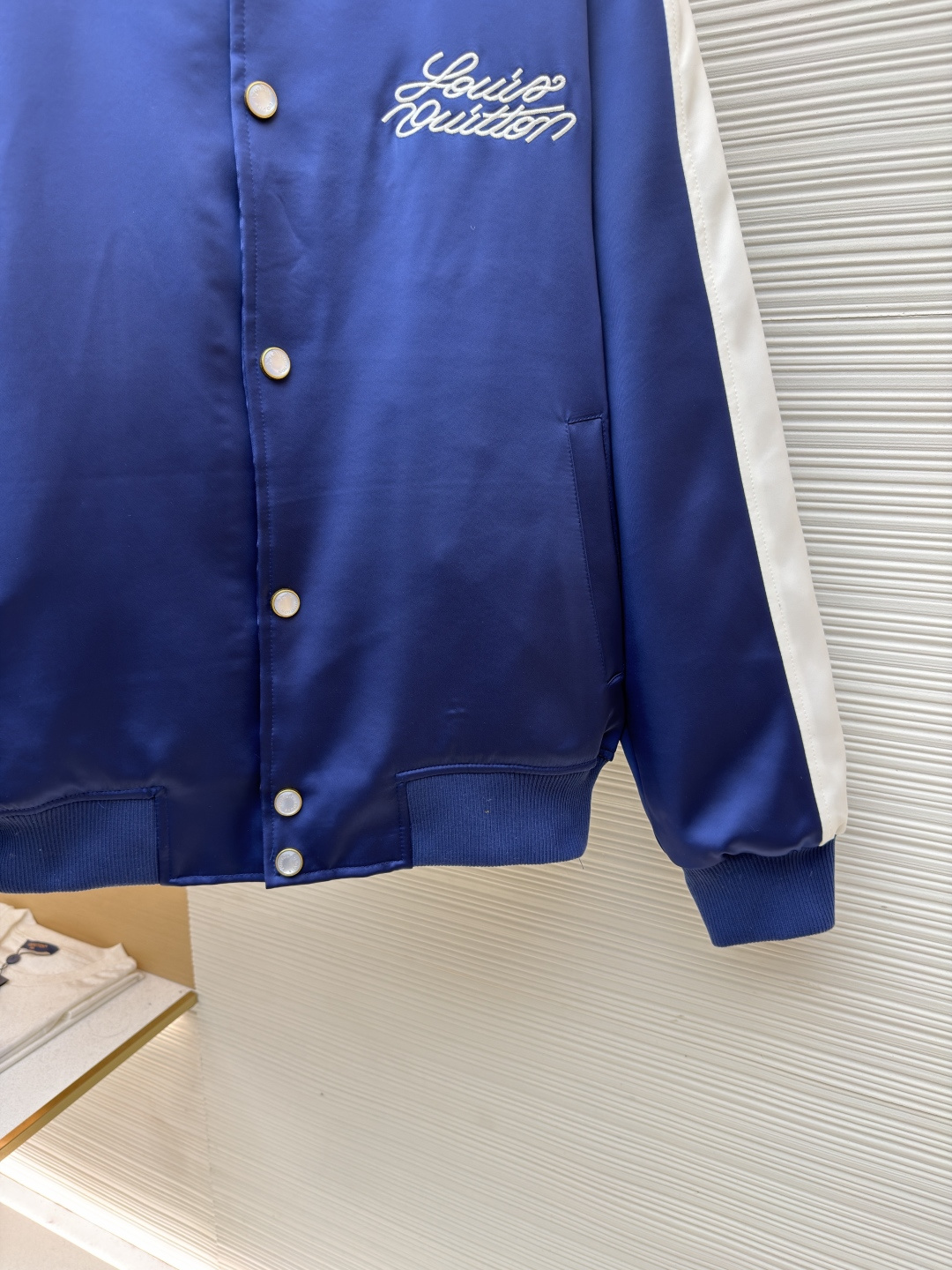 P325 LOUIS VUITTON 马年限定撞色饰带刺绣单排扣长袖夹克
●原版：27975购入开发
●货号：1682618-B90
●面料：全棉面料
●工艺：刺绣制作
●颜色：蓝白
●版型：合身版型
●克重：约1165克
●尺码：46-48-50-52
●描述：这款LV马年限定撞色饰带刺绣夹克，采用重磅哑光缎面面料，兼具挺括垂坠感与柔滑触感，表面经抗皱防泼水处理，日常打理便捷。立领与袖口、下摆采用高弹罗纹针织，紧密贴合且不易松弛变形，门襟选用定制哑光金属单排扣，扣面刻有品牌标识，兼具质感与辨识度。肩部与袖身的撞色饰带采用斜纹拼接工艺，边缘经包边处理避免脱线，左胸的品牌标识采用立体刺绣工艺，以多股线迹呈现饱满纹理，内里采用透气衬里，所有缝线处均做包边与锁边处理，整体工艺将传统棒球服版型与马年专属设计元素结合，兼具典藏价值与实穿性。整体走线平直细腻，面料舒适柔软，颜色一致无色差 能与同款搭配营造时尚造型，驾驭各种场合，定制辅料，三标齐全，男女同款！