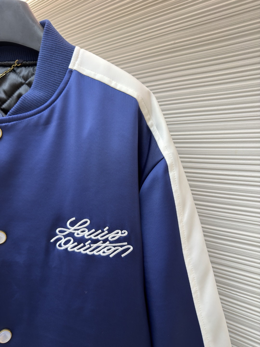 P325 LOUIS VUITTON 马年限定撞色饰带刺绣单排扣长袖夹克
●原版：27975购入开发
●货号：1682618-B90
●面料：全棉面料
●工艺：刺绣制作
●颜色：蓝白
●版型：合身版型
●克重：约1165克
●尺码：46-48-50-52
●描述：这款LV马年限定撞色饰带刺绣夹克，采用重磅哑光缎面面料，兼具挺括垂坠感与柔滑触感，表面经抗皱防泼水处理，日常打理便捷。立领与袖口、下摆采用高弹罗纹针织，紧密贴合且不易松弛变形，门襟选用定制哑光金属单排扣，扣面刻有品牌标识，兼具质感与辨识度。肩部与袖身的撞色饰带采用斜纹拼接工艺，边缘经包边处理避免脱线，左胸的品牌标识采用立体刺绣工艺，以多股线迹呈现饱满纹理，内里采用透气衬里，所有缝线处均做包边与锁边处理，整体工艺将传统棒球服版型与马年专属设计元素结合，兼具典藏价值与实穿性。整体走线平直细腻，面料舒适柔软，颜色一致无色差 能与同款搭配营造时尚造型，驾驭各种场合，定制辅料，三标齐全，男女同款！