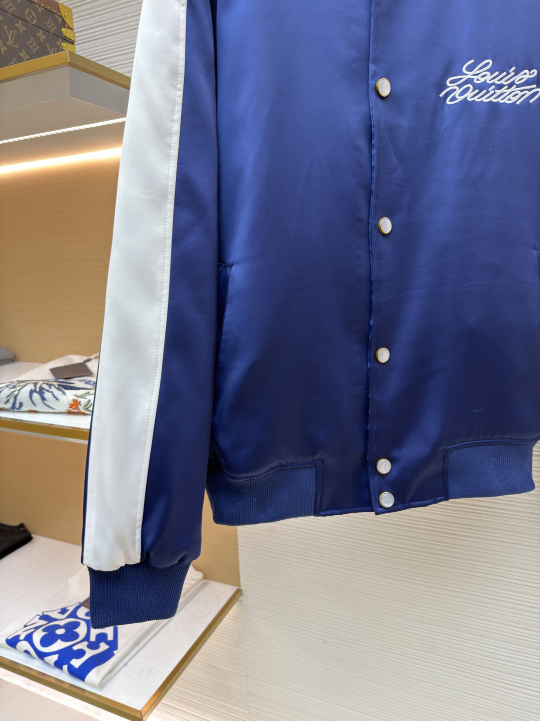 P325 LOUIS VUITTON 马年限定撞色饰带刺绣单排扣长袖夹克
●原版：27975购入开发
●货号：1682618-B90
●面料：全棉面料
●工艺：刺绣制作
●颜色：蓝白
●版型：合身版型
●克重：约1165克
●尺码：46-48-50-52
●描述：这款LV马年限定撞色饰带刺绣夹克，采用重磅哑光缎面面料，兼具挺括垂坠感与柔滑触感，表面经抗皱防泼水处理，日常打理便捷。立领与袖口、下摆采用高弹罗纹针织，紧密贴合且不易松弛变形，门襟选用定制哑光金属单排扣，扣面刻有品牌标识，兼具质感与辨识度。肩部与袖身的撞色饰带采用斜纹拼接工艺，边缘经包边处理避免脱线，左胸的品牌标识采用立体刺绣工艺，以多股线迹呈现饱满纹理，内里采用透气衬里，所有缝线处均做包边与锁边处理，整体工艺将传统棒球服版型与马年专属设计元素结合，兼具典藏价值与实穿性。整体走线平直细腻，面料舒适柔软，颜色一致无色差 能与同款搭配营造时尚造型，驾驭各种场合，定制辅料，三标齐全，男女同款！