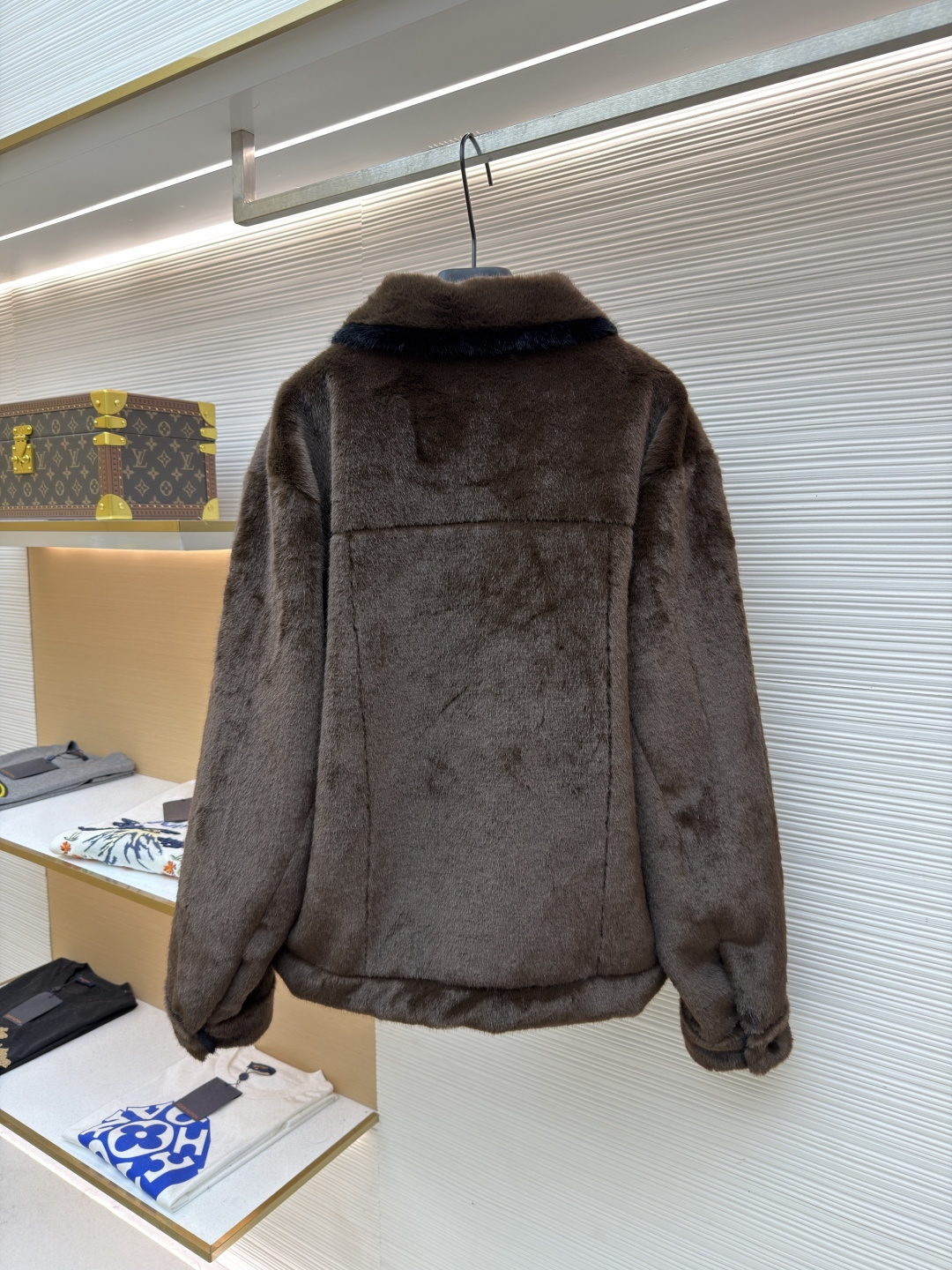 P455 LOUIS VUITTON 纯色长袖尖领皮草
●原版：171000购入开发
●货号：1682619-D15
●面料：水貂毛面料
●工艺：定位裁床制作
●颜色：棕色
●版型：合身版型
●克重：约1220克
●尺码：46-48-50-52
●描述：这款LV棕色仿水貂毛翻领夹克，采用高密仿水貂毛绒面料，绒毛浓密且富有光泽，触感柔软亲肤，兼具保暖性与高级质感。翻领设计沿用经典工装版型，领面与衣身采用同料一体剪裁，边缘经锁边处理防止脱线。门襟选用复古铜色金属按扣，扣面光滑且耐用，两侧翻盖口袋采用隐形缝线工艺，袋口的金属扣与门襟扣呼应，增强整体协调感。左胸的品牌标识牌采用真皮压印工艺，与毛绒面料形成材质对比，袖口与下摆的弹力包边紧密贴合身形，内里采用亲肤衬里避免静电，所有接缝处均做双针加固，兼顾保暖性与工装风格的硬朗质感，是冬季兼具造型感与实用性的单品。整体走线平直细腻，面料舒适柔软，颜色一致无色差 能与同款搭配营造时尚造型，驾驭各种场合，定制辅料，三标齐全，男女同款！
