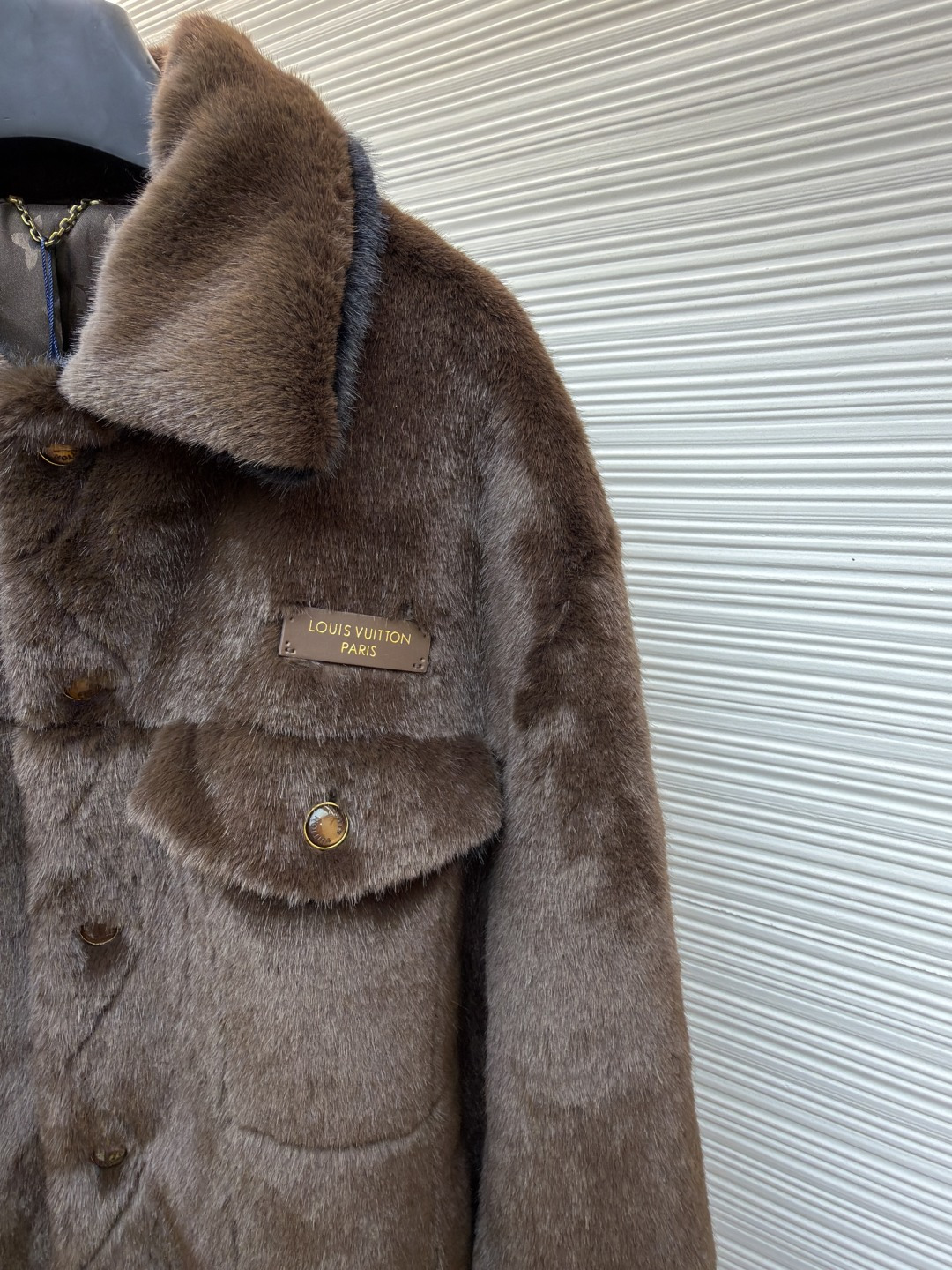 P455 LOUIS VUITTON 纯色长袖尖领皮草
●原版：171000购入开发
●货号：1682619-D15
●面料：水貂毛面料
●工艺：定位裁床制作
●颜色：棕色
●版型：合身版型
●克重：约1220克
●尺码：46-48-50-52
●描述：这款LV棕色仿水貂毛翻领夹克，采用高密仿水貂毛绒面料，绒毛浓密且富有光泽，触感柔软亲肤，兼具保暖性与高级质感。翻领设计沿用经典工装版型，领面与衣身采用同料一体剪裁，边缘经锁边处理防止脱线。门襟选用复古铜色金属按扣，扣面光滑且耐用，两侧翻盖口袋采用隐形缝线工艺，袋口的金属扣与门襟扣呼应，增强整体协调感。左胸的品牌标识牌采用真皮压印工艺，与毛绒面料形成材质对比，袖口与下摆的弹力包边紧密贴合身形，内里采用亲肤衬里避免静电，所有接缝处均做双针加固，兼顾保暖性与工装风格的硬朗质感，是冬季兼具造型感与实用性的单品。整体走线平直细腻，面料舒适柔软，颜色一致无色差 能与同款搭配营造时尚造型，驾驭各种场合，定制辅料，三标齐全，男女同款！