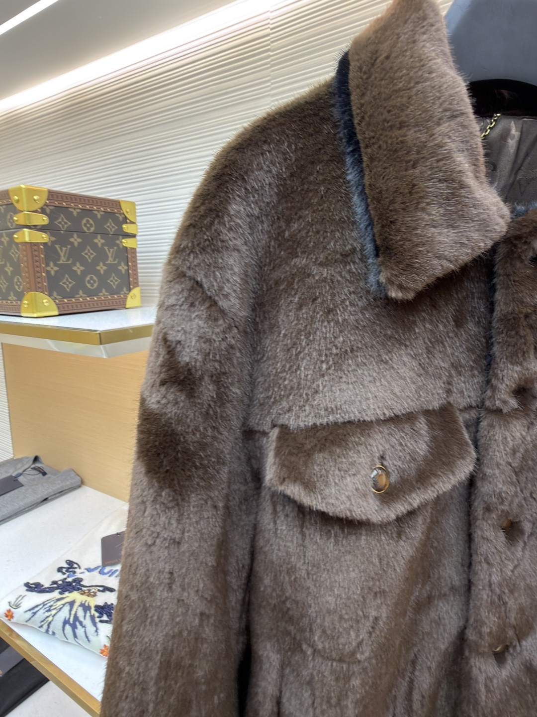 P455 LOUIS VUITTON 纯色长袖尖领皮草
●原版：171000购入开发
●货号：1682619-D15
●面料：水貂毛面料
●工艺：定位裁床制作
●颜色：棕色
●版型：合身版型
●克重：约1220克
●尺码：46-48-50-52
●描述：这款LV棕色仿水貂毛翻领夹克，采用高密仿水貂毛绒面料，绒毛浓密且富有光泽，触感柔软亲肤，兼具保暖性与高级质感。翻领设计沿用经典工装版型，领面与衣身采用同料一体剪裁，边缘经锁边处理防止脱线。门襟选用复古铜色金属按扣，扣面光滑且耐用，两侧翻盖口袋采用隐形缝线工艺，袋口的金属扣与门襟扣呼应，增强整体协调感。左胸的品牌标识牌采用真皮压印工艺，与毛绒面料形成材质对比，袖口与下摆的弹力包边紧密贴合身形，内里采用亲肤衬里避免静电，所有接缝处均做双针加固，兼顾保暖性与工装风格的硬朗质感，是冬季兼具造型感与实用性的单品。整体走线平直细腻，面料舒适柔软，颜色一致无色差 能与同款搭配营造时尚造型，驾驭各种场合，定制辅料，三标齐全，男女同款！