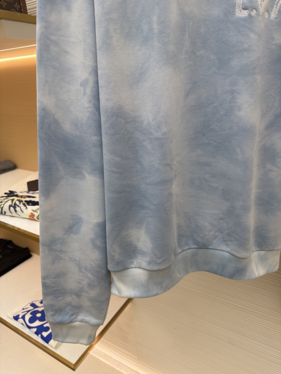 P205 LOUIS VUITTON 云朵扎染圆领卫衣
●原版：12883购入开发
●货号：1682620-A75
●面料：全棉面料
●工艺：扎染漂白制作
●颜色：蓝白
●版型：合身版型
●克重：约550克
●尺码：XS-S-M-L
●描述：面料采用26S双纱+10S鱼鳞底磨毛面料，克重380g/㎡，搭配21S双纱2*2罗纹，克重470g/㎡。这种面料通过起绒处理，内侧会形成一层柔软丰盈的绒毛；改良的鱼鳞状针织法在底面形成细腻的凹凸肌理，类似鱼鳞排列。有效增加空气储存层，提升保暖性能。面料正面光洁平整，背面柔软丰糯，兼具出色吸湿透气性、抗皱性与垂坠感，比普通卫衣料更显厚实挺括。赋予衣物极佳的保暖性、透气性和亲肤触感。通过捆扎、缝纫或夹板等方式对成衣或面料进行物理防染，然后进行染色。被捆扎的部分染料无法渗入，从而形成独特、不规则且每件都不重复的晕染纹理和图案。通过可控的化学漂洗或酶洗工艺，模拟阳光长期照射后产生的局部褪色效果，形成柔和、自然的色彩层次。这两种工艺共同作用，使每件T恤都拥有独一无二的别致观感，奠定了单品艺术化和手工感的基调。整体走线平直细腻，面料舒适柔软，颜色一致无色差 能与同款搭配营造时尚造型，驾驭各种场合，定制辅料，三标齐全，男女同款！