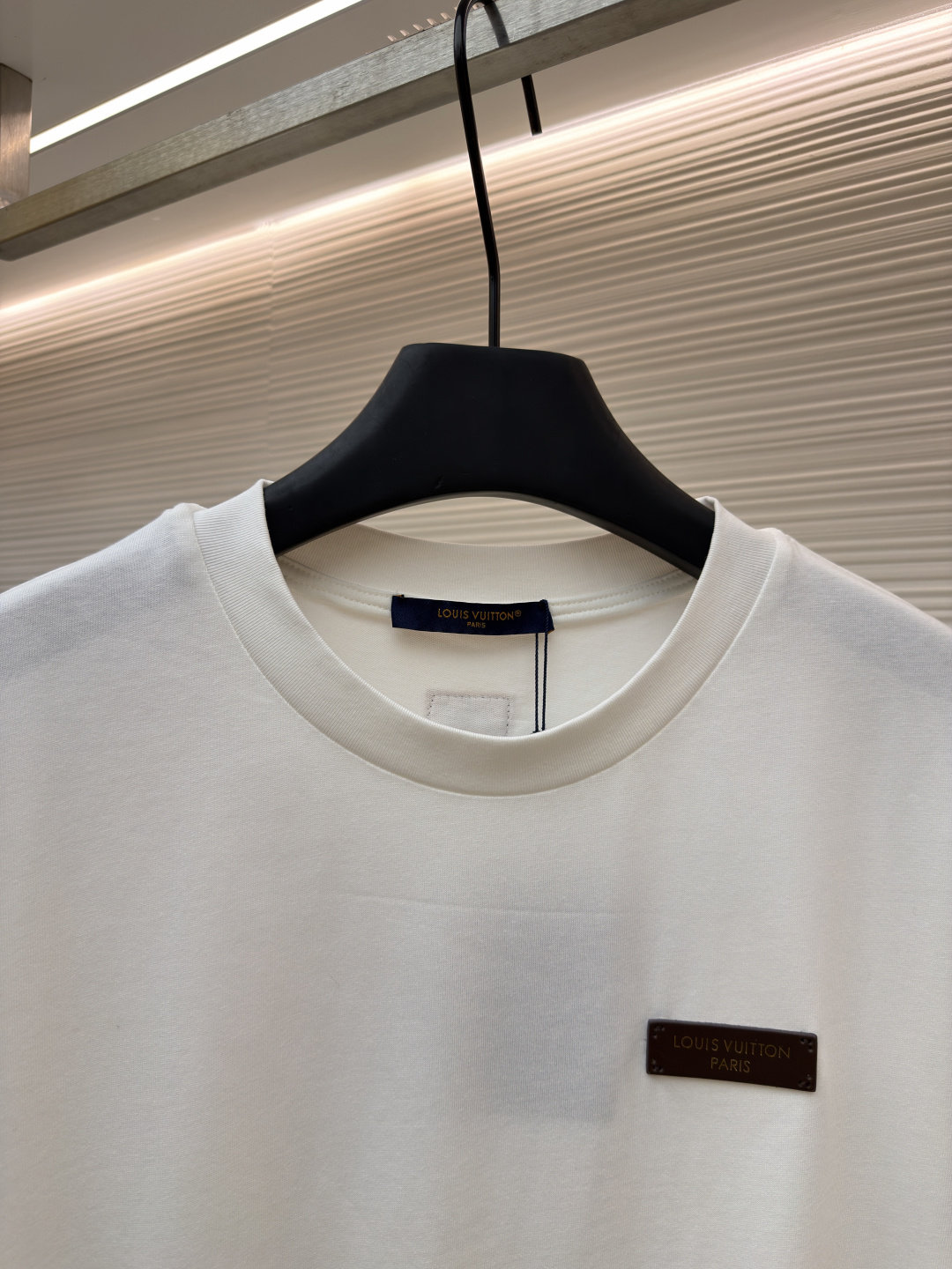 P125 LOUIS VUITTON 皮标标识短袖
●货号：1682622-A00
●面料：全棉面料
●工艺：手工缝标制作
●颜色：白色
●版型：合身版型
●克重：约255克
●尺码：S-M-L-XL
●描述：这款LV白色短袖T恤采用高支双股精梳棉面料，经预缩水处理，触感柔软亲肤且久洗不易变形，圆领采用双层罗纹针织工艺，弹力适中贴合颈部，边缘经加固锁边处理防止松弛卷边。左胸的品牌标识牌选用头层牛皮材质，表面压印品牌标识，通过高温热压工艺与衣身牢固贴合，兼具辨识度与高级质感。衣身采用平缝工艺拼接，缝线细密平整，袖口与下摆采用同料包边处理，避免磨损脱线，整体版型为宽松落肩设计，兼顾舒适体感与简约调性，所有细节均遵循品牌严苛工艺标准，是兼具实穿性与品牌辨识度的日常单品。整体走线平直细腻，面料舒适柔软，颜色一致无色差 能与同款搭配营造时尚造型，驾驭各种场合，定制辅料，三标齐全，男女同款！