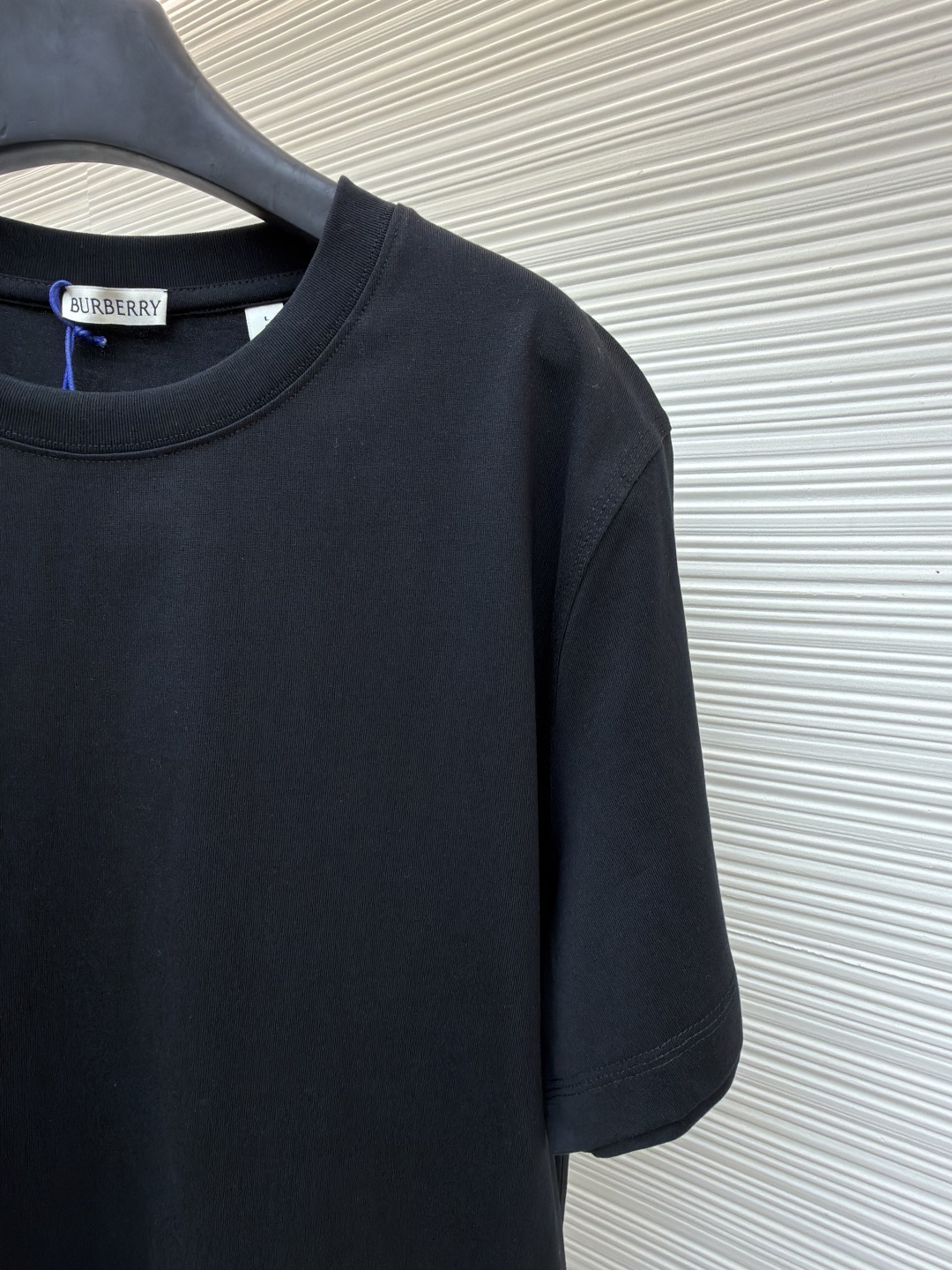 P110 Burberry 经典圆领人字车标格纹标签棉质T恤衫
●原版：3350购入开发
●货号：1682624-X85
●面料：全棉面料
●工艺：人字车标制作
●颜色：黑色
●版型：合身版型
●克重：约265克
●尺码：S-M-L-XL
●描述：此款T恤采用高支精梳棉质面料为基底，经过酵素洗水工艺处理，使面料触感更柔软亲肤，同时增强了成衣的抗皱性与穿着舒适度。领口采用双针包边工艺，搭配加固缝线，耐洗不易变形，贴合颈部曲线的同时保证了持久的穿着寿命。衣身侧面的标志性格纹标签采用精密锁边工艺固定，边缘平整牢固；胸前的品牌标识则以人字车线工艺缝制，针脚细密均匀、线条流畅立体，兼具装饰性与辨识度。整体剪裁为宽松版型，车线工整且线头处理干净，结合专业的预缩水处理，有效降低了穿着洗涤后的缩水率，建议手洗以更好地保护面料与精致工艺。整体走线平直细腻，面料舒适柔软，颜色一致无色差 能与同款搭配营造时尚造型，驾驭各种场合，定制辅料，三标齐全，男女同款！