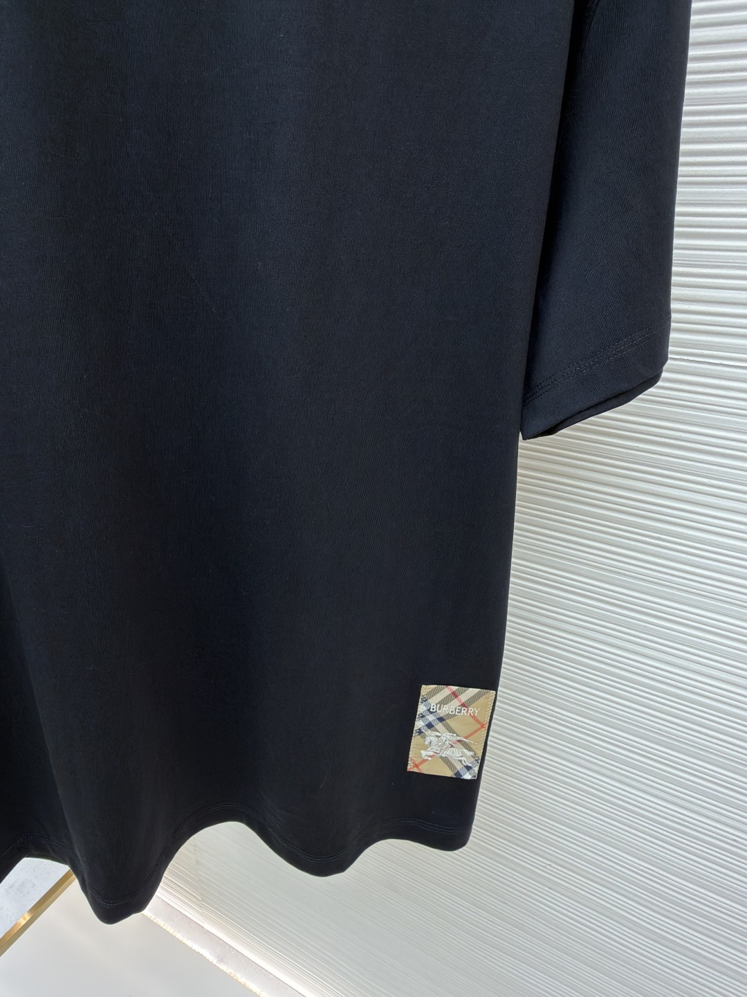 P110 Burberry 经典圆领人字车标格纹标签棉质T恤衫
●原版：3350购入开发
●货号：1682624-X85
●面料：全棉面料
●工艺：人字车标制作
●颜色：黑色
●版型：合身版型
●克重：约265克
●尺码：S-M-L-XL
●描述：此款T恤采用高支精梳棉质面料为基底，经过酵素洗水工艺处理，使面料触感更柔软亲肤，同时增强了成衣的抗皱性与穿着舒适度。领口采用双针包边工艺，搭配加固缝线，耐洗不易变形，贴合颈部曲线的同时保证了持久的穿着寿命。衣身侧面的标志性格纹标签采用精密锁边工艺固定，边缘平整牢固；胸前的品牌标识则以人字车线工艺缝制，针脚细密均匀、线条流畅立体，兼具装饰性与辨识度。整体剪裁为宽松版型，车线工整且线头处理干净，结合专业的预缩水处理，有效降低了穿着洗涤后的缩水率，建议手洗以更好地保护面料与精致工艺。整体走线平直细腻，面料舒适柔软，颜色一致无色差 能与同款搭配营造时尚造型，驾驭各种场合，定制辅料，三标齐全，男女同款！