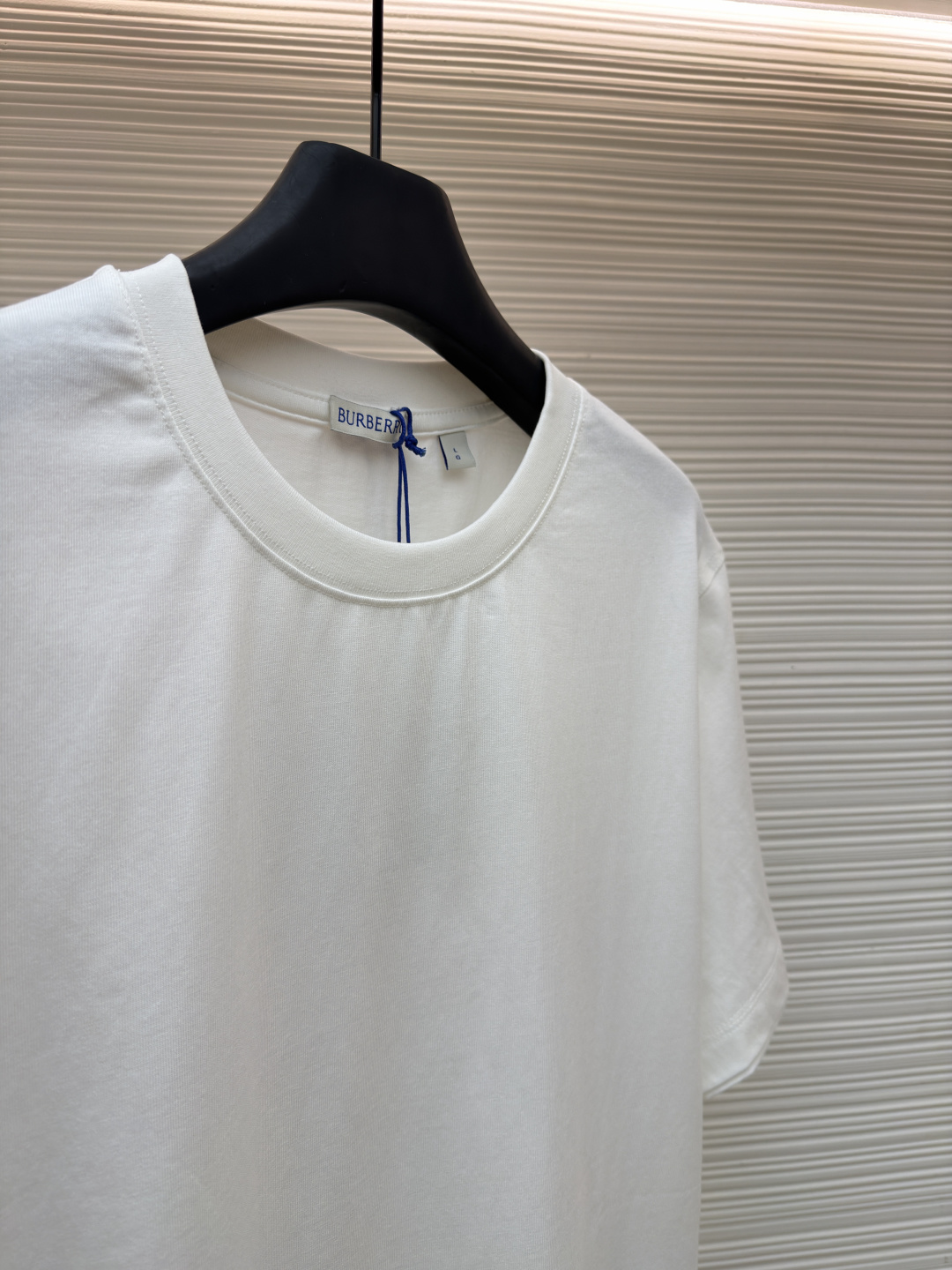 P110 Burberry 经典圆领人字车标格纹标签棉质T恤衫
●原版：3350购入开发
●货号：1682625-X85
●面料：全棉面料
●工艺：人字车标制作
●颜色：白色
●版型：合身版型
●克重：约255克
●尺码：S-M-L-XL
●描述：此款T恤采用高支精梳棉质面料为基底，经过酵素洗水工艺处理，使面料触感更柔软亲肤，同时增强了成衣的抗皱性与穿着舒适度。领口采用双针包边工艺，搭配加固缝线，耐洗不易变形，贴合颈部曲线的同时保证了持久的穿着寿命。衣身侧面的标志性格纹标签采用精密锁边工艺固定，边缘平整牢固；胸前的品牌标识则以人字车线工艺缝制，针脚细密均匀、线条流畅立体，兼具装饰性与辨识度。整体剪裁为宽松版型，车线工整且线头处理干净，结合专业的预缩水处理，有效降低了穿着洗涤后的缩水率，建议手洗以更好地保护面料与精致工艺。整体走线平直细腻，面料舒适柔软，颜色一致无色差 能与同款搭配营造时尚造型，驾驭各种场合，定制辅料，三标齐全，男女同款！