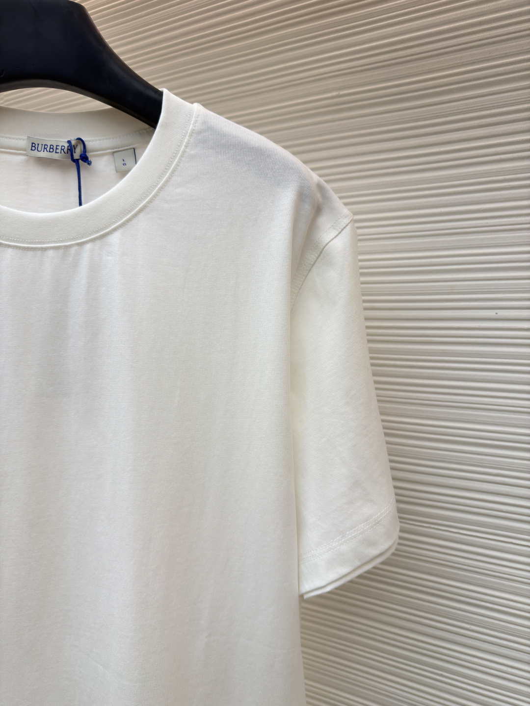 P110 Burberry 经典圆领人字车标格纹标签棉质T恤衫
●原版：3350购入开发
●货号：1682625-X85
●面料：全棉面料
●工艺：人字车标制作
●颜色：白色
●版型：合身版型
●克重：约255克
●尺码：S-M-L-XL
●描述：此款T恤采用高支精梳棉质面料为基底，经过酵素洗水工艺处理，使面料触感更柔软亲肤，同时增强了成衣的抗皱性与穿着舒适度。领口采用双针包边工艺，搭配加固缝线，耐洗不易变形，贴合颈部曲线的同时保证了持久的穿着寿命。衣身侧面的标志性格纹标签采用精密锁边工艺固定，边缘平整牢固；胸前的品牌标识则以人字车线工艺缝制，针脚细密均匀、线条流畅立体，兼具装饰性与辨识度。整体剪裁为宽松版型，车线工整且线头处理干净，结合专业的预缩水处理，有效降低了穿着洗涤后的缩水率，建议手洗以更好地保护面料与精致工艺。整体走线平直细腻，面料舒适柔软，颜色一致无色差 能与同款搭配营造时尚造型，驾驭各种场合，定制辅料，三标齐全，男女同款！