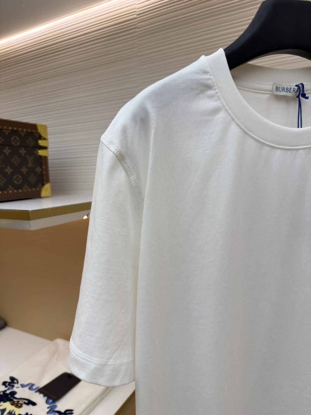 P110 Burberry 经典圆领人字车标格纹标签棉质T恤衫
●原版：3350购入开发
●货号：1682625-X85
●面料：全棉面料
●工艺：人字车标制作
●颜色：白色
●版型：合身版型
●克重：约255克
●尺码：S-M-L-XL
●描述：此款T恤采用高支精梳棉质面料为基底，经过酵素洗水工艺处理，使面料触感更柔软亲肤，同时增强了成衣的抗皱性与穿着舒适度。领口采用双针包边工艺，搭配加固缝线，耐洗不易变形，贴合颈部曲线的同时保证了持久的穿着寿命。衣身侧面的标志性格纹标签采用精密锁边工艺固定，边缘平整牢固；胸前的品牌标识则以人字车线工艺缝制，针脚细密均匀、线条流畅立体，兼具装饰性与辨识度。整体剪裁为宽松版型，车线工整且线头处理干净，结合专业的预缩水处理，有效降低了穿着洗涤后的缩水率，建议手洗以更好地保护面料与精致工艺。整体走线平直细腻，面料舒适柔软，颜色一致无色差 能与同款搭配营造时尚造型，驾驭各种场合，定制辅料，三标齐全，男女同款！