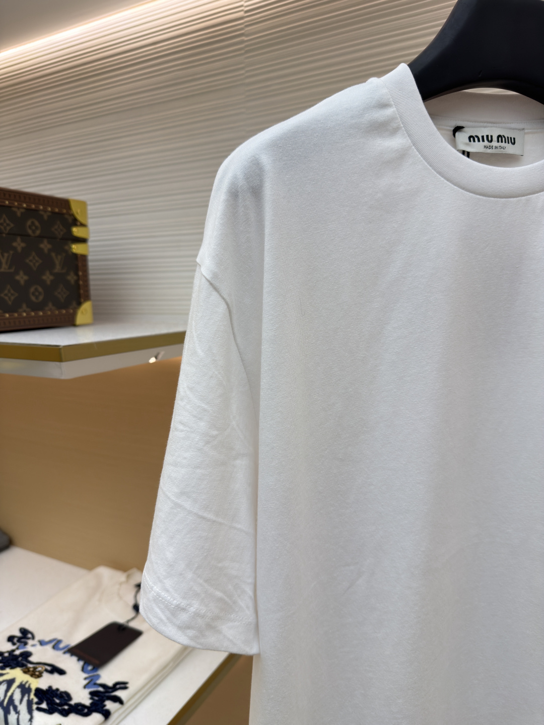 P125 MIU MIU经典字母logo图案短袖
●原版：5350购入开发
●货号：1682626-A00
●面料：精梳棉面料
●工艺：刺绣制作
●颜色：白色
●版型：合身版型
●克重：约220克
●尺码：S-M-L-XL
●描述：这款MIU MIU字母LOGO图案短袖以高支数精梳棉为面料基底，通过酵素洗水工艺处理，使布面触感更柔软顺滑，同时提升了面料的抗皱性与透气性，减少穿着紧绷感。胸前的品牌字母LOGO采用进口刺绣工艺，选用高光泽度的优质绣线，针脚细密均匀、图案立体饱满，兼具细腻质感与品牌辨识度，且经加固处理不易脱线。领口采用双针包边工艺，搭配同色系缝线，耐洗不易变形，贴合颈部曲线的同时保障了穿着舒适度。整体剪裁为宽松落肩版型，车线工整且线头处理干净，结合预缩水处理有效降低了洗涤后的缩水率，建议手洗以更好地保护刺绣细节与面料质感。整体走线平直细腻，面料舒适柔软，颜色一致无色差 能与同款搭配营造时尚造型，驾驭各种场合，定制辅料，三标齐全，男女同款！