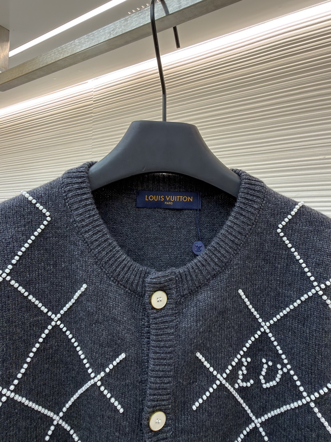 p610 LOUIS VUITTON 字母串珠格纹针织开衫毛衣
●原版：18049购入开发
●面料：羊毛面料
●工艺：针织制作
●颜色：灰色
●版型：合身版型
●克重：约790克
●尺码：S-M-L-XL
●描述：这款圆领开衫采用重磅羊毛混纺面料，深灰色基底质感软糯且保暖性优异，衣身通过手工钉珠工艺打造出立体菱格纹图案，每颗珍珠饰钉经精密定位固定，牢固不易脱落，兼具精致感与辨识度。门襟选用定制天然贝母纽扣，光泽细腻且开合顺滑，圆领及袖口、下摆均采用同色系高弹罗纹收边，经过预缩水处理，久穿不易变形松垮。衣身采用德国斯托尔针织机一体成型工艺，减少拼接缝线，穿着更贴合舒适，同时通过抗起球处理，日常穿着不易起毛起球，整体版型为微宽松剪裁，适配多种身形，是打造秋冬精致通勤造型的质感单品。整体走线平直细腻，面料舒适柔软，颜色一致无色差 能与同款搭配营造时尚造型，驾驭各种场合，定制辅料，三标齐全，男女同款！