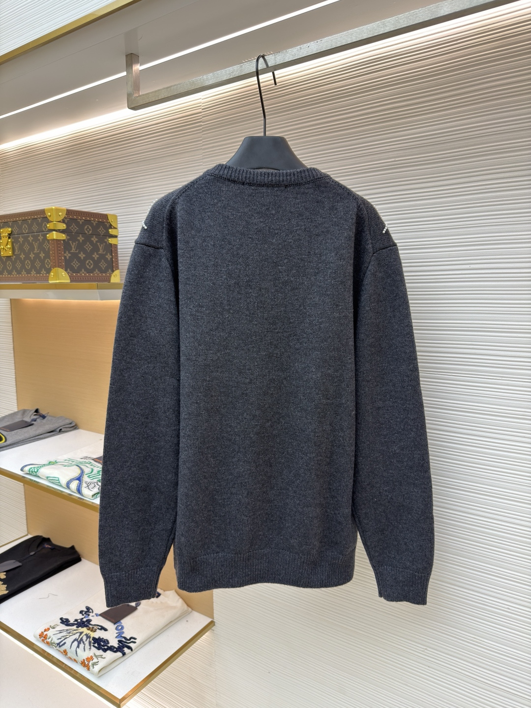 p610 LOUIS VUITTON 字母串珠格纹针织开衫毛衣
●原版：18049购入开发
●面料：羊毛面料
●工艺：针织制作
●颜色：灰色
●版型：合身版型
●克重：约790克
●尺码：S-M-L-XL
●描述：这款圆领开衫采用重磅羊毛混纺面料，深灰色基底质感软糯且保暖性优异，衣身通过手工钉珠工艺打造出立体菱格纹图案，每颗珍珠饰钉经精密定位固定，牢固不易脱落，兼具精致感与辨识度。门襟选用定制天然贝母纽扣，光泽细腻且开合顺滑，圆领及袖口、下摆均采用同色系高弹罗纹收边，经过预缩水处理，久穿不易变形松垮。衣身采用德国斯托尔针织机一体成型工艺，减少拼接缝线，穿着更贴合舒适，同时通过抗起球处理，日常穿着不易起毛起球，整体版型为微宽松剪裁，适配多种身形，是打造秋冬精致通勤造型的质感单品。整体走线平直细腻，面料舒适柔软，颜色一致无色差 能与同款搭配营造时尚造型，驾驭各种场合，定制辅料，三标齐全，男女同款！