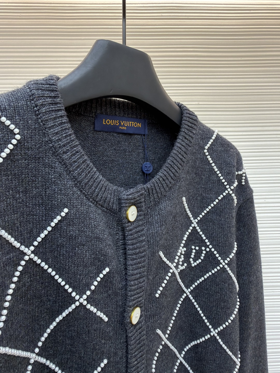p610 LOUIS VUITTON 字母串珠格纹针织开衫毛衣
●原版：18049购入开发
●面料：羊毛面料
●工艺：针织制作
●颜色：灰色
●版型：合身版型
●克重：约790克
●尺码：S-M-L-XL
●描述：这款圆领开衫采用重磅羊毛混纺面料，深灰色基底质感软糯且保暖性优异，衣身通过手工钉珠工艺打造出立体菱格纹图案，每颗珍珠饰钉经精密定位固定，牢固不易脱落，兼具精致感与辨识度。门襟选用定制天然贝母纽扣，光泽细腻且开合顺滑，圆领及袖口、下摆均采用同色系高弹罗纹收边，经过预缩水处理，久穿不易变形松垮。衣身采用德国斯托尔针织机一体成型工艺，减少拼接缝线，穿着更贴合舒适，同时通过抗起球处理，日常穿着不易起毛起球，整体版型为微宽松剪裁，适配多种身形，是打造秋冬精致通勤造型的质感单品。整体走线平直细腻，面料舒适柔软，颜色一致无色差 能与同款搭配营造时尚造型，驾驭各种场合，定制辅料，三标齐全，男女同款！