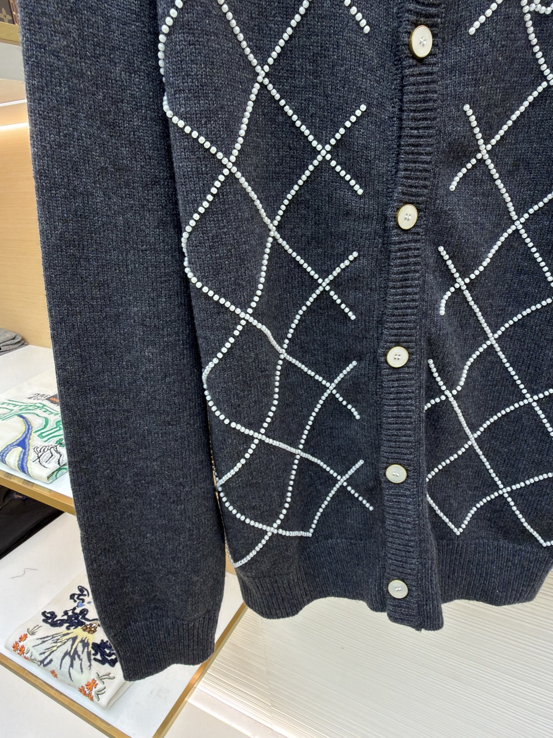 p610 LOUIS VUITTON 字母串珠格纹针织开衫毛衣
●原版：18049购入开发
●面料：羊毛面料
●工艺：针织制作
●颜色：灰色
●版型：合身版型
●克重：约790克
●尺码：S-M-L-XL
●描述：这款圆领开衫采用重磅羊毛混纺面料，深灰色基底质感软糯且保暖性优异，衣身通过手工钉珠工艺打造出立体菱格纹图案，每颗珍珠饰钉经精密定位固定，牢固不易脱落，兼具精致感与辨识度。门襟选用定制天然贝母纽扣，光泽细腻且开合顺滑，圆领及袖口、下摆均采用同色系高弹罗纹收边，经过预缩水处理，久穿不易变形松垮。衣身采用德国斯托尔针织机一体成型工艺，减少拼接缝线，穿着更贴合舒适，同时通过抗起球处理，日常穿着不易起毛起球，整体版型为微宽松剪裁，适配多种身形，是打造秋冬精致通勤造型的质感单品。整体走线平直细腻，面料舒适柔软，颜色一致无色差 能与同款搭配营造时尚造型，驾驭各种场合，定制辅料，三标齐全，男女同款！