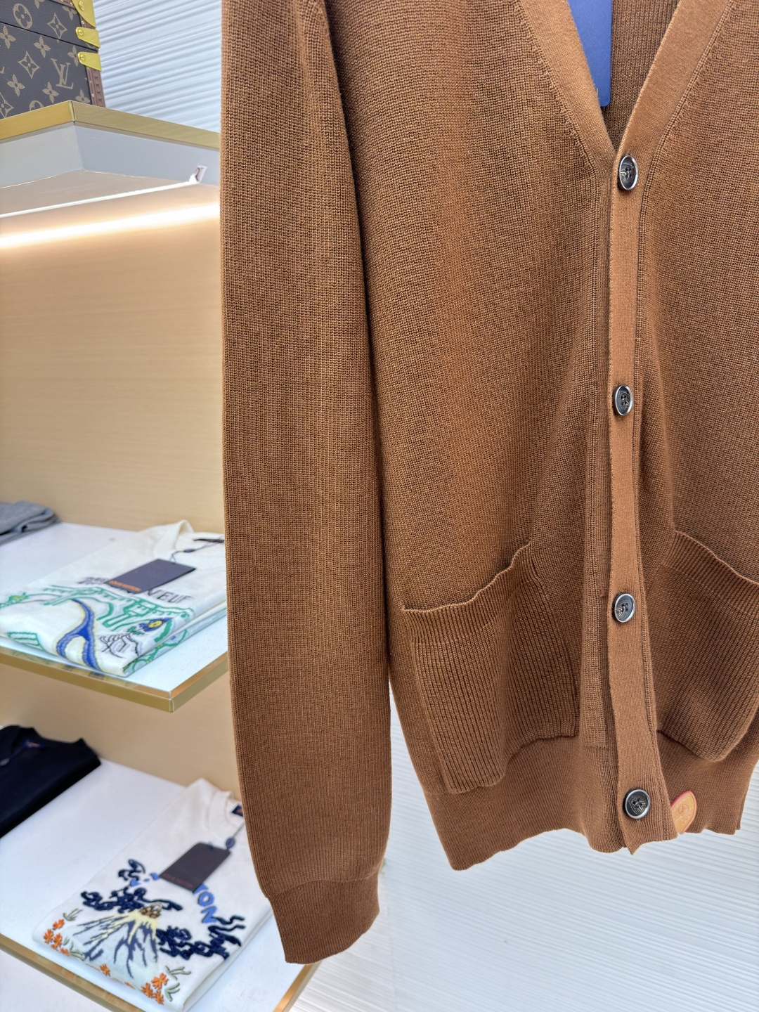 p400 LOUIS VUITTON 字母徽章标识针织V领开衫毛衣
●面料：羊毛面料
●工艺：针织制作
●颜色：棕色
●版型：合身版型
●克重：约535克
●尺码：S-M-L-XL
●描述：这款焦糖棕V领开衫采用高支数羊毛混纺针织面料，经双股线精密织造，兼具保暖性与透气性，表面纹理细腻且抗起球性能优异，色牢度达4.5级以上，久穿不易褪色变形。V领采用包边嵌条工艺，领口挺括不易变形；门襟选用四颗哑光质感的定制金属纽扣，扣眼采用加固锁边工艺，耐用性更强。衣身两侧嵌缝立体贴袋，袋口做双针明线加固，兼具实用性与美观度；袖口及下摆采用罗纹收边，弹力适中贴合身形且不易松弛。成衣经过整烫定型、线头修剪等多道后整理工序，针脚均匀细密，走线流畅无跳线，整体版型宽松有度，日常穿搭舒适随性，适配多种风格场景。整体走线平直细腻，面料舒适柔软，颜色一致无色差 能与同款搭配营造时尚造型，驾驭各种场合，定制辅料，三标齐全，男女同款！