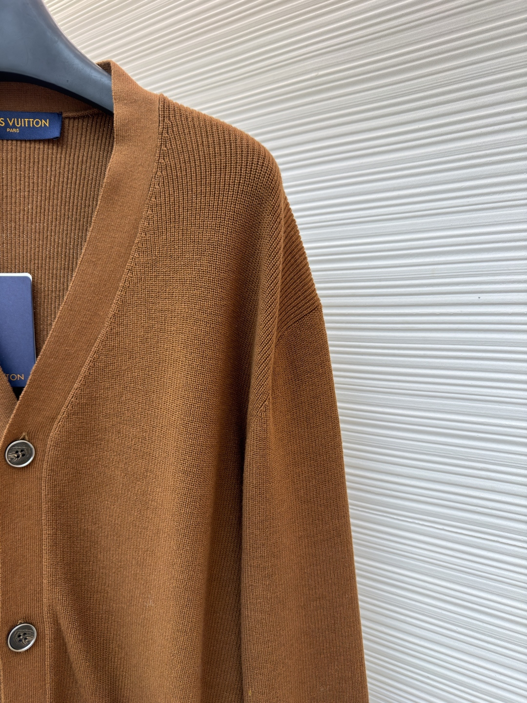 p400 LOUIS VUITTON 字母徽章标识针织V领开衫毛衣
●面料：羊毛面料
●工艺：针织制作
●颜色：棕色
●版型：合身版型
●克重：约535克
●尺码：S-M-L-XL
●描述：这款焦糖棕V领开衫采用高支数羊毛混纺针织面料，经双股线精密织造，兼具保暖性与透气性，表面纹理细腻且抗起球性能优异，色牢度达4.5级以上，久穿不易褪色变形。V领采用包边嵌条工艺，领口挺括不易变形；门襟选用四颗哑光质感的定制金属纽扣，扣眼采用加固锁边工艺，耐用性更强。衣身两侧嵌缝立体贴袋，袋口做双针明线加固，兼具实用性与美观度；袖口及下摆采用罗纹收边，弹力适中贴合身形且不易松弛。成衣经过整烫定型、线头修剪等多道后整理工序，针脚均匀细密，走线流畅无跳线，整体版型宽松有度，日常穿搭舒适随性，适配多种风格场景。整体走线平直细腻，面料舒适柔软，颜色一致无色差 能与同款搭配营造时尚造型，驾驭各种场合，定制辅料，三标齐全，男女同款！