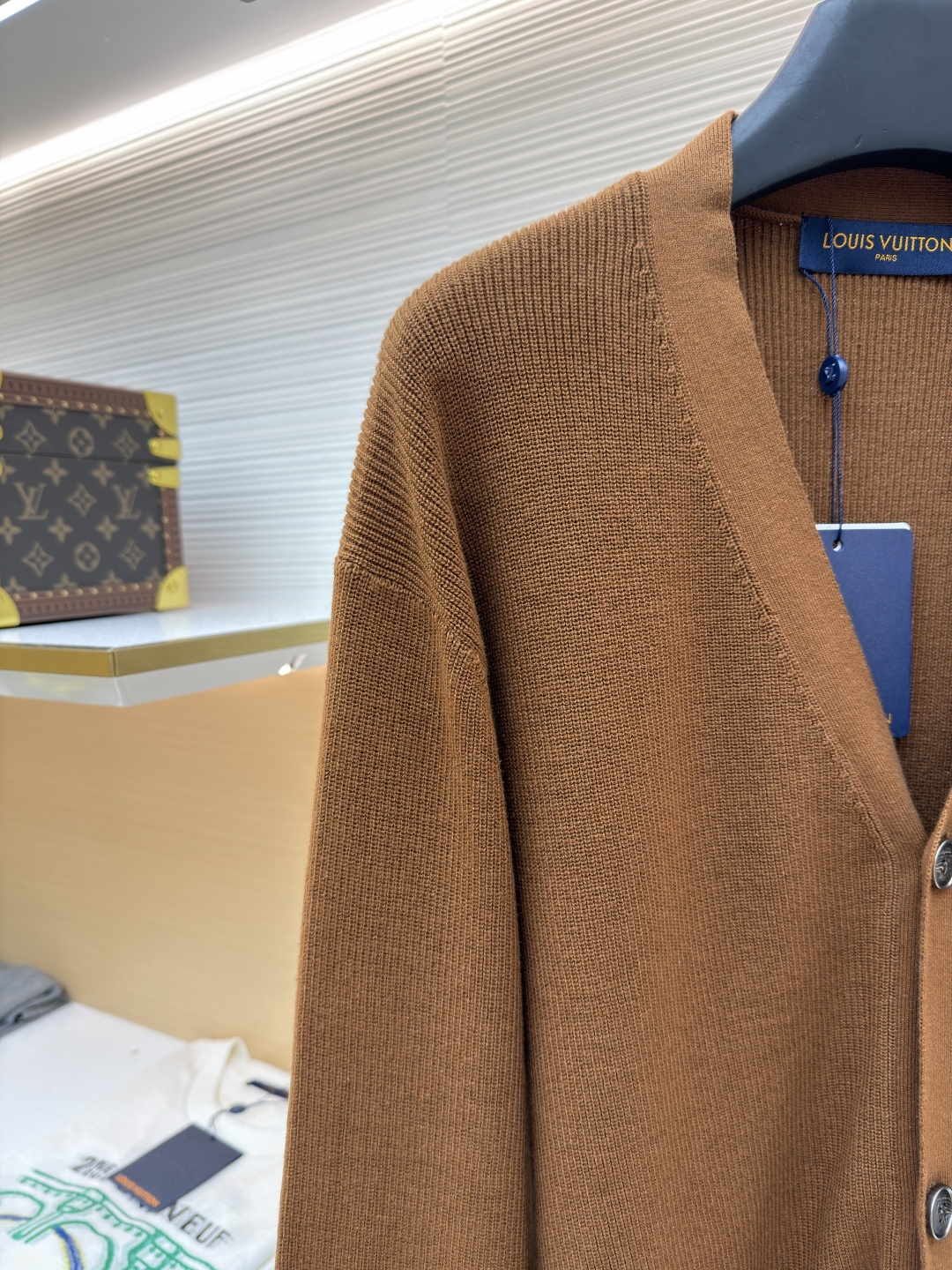 p400 LOUIS VUITTON 字母徽章标识针织V领开衫毛衣
●面料：羊毛面料
●工艺：针织制作
●颜色：棕色
●版型：合身版型
●克重：约535克
●尺码：S-M-L-XL
●描述：这款焦糖棕V领开衫采用高支数羊毛混纺针织面料，经双股线精密织造，兼具保暖性与透气性，表面纹理细腻且抗起球性能优异，色牢度达4.5级以上，久穿不易褪色变形。V领采用包边嵌条工艺，领口挺括不易变形；门襟选用四颗哑光质感的定制金属纽扣，扣眼采用加固锁边工艺，耐用性更强。衣身两侧嵌缝立体贴袋，袋口做双针明线加固，兼具实用性与美观度；袖口及下摆采用罗纹收边，弹力适中贴合身形且不易松弛。成衣经过整烫定型、线头修剪等多道后整理工序，针脚均匀细密，走线流畅无跳线，整体版型宽松有度，日常穿搭舒适随性，适配多种风格场景。整体走线平直细腻，面料舒适柔软，颜色一致无色差 能与同款搭配营造时尚造型，驾驭各种场合，定制辅料，三标齐全，男女同款！